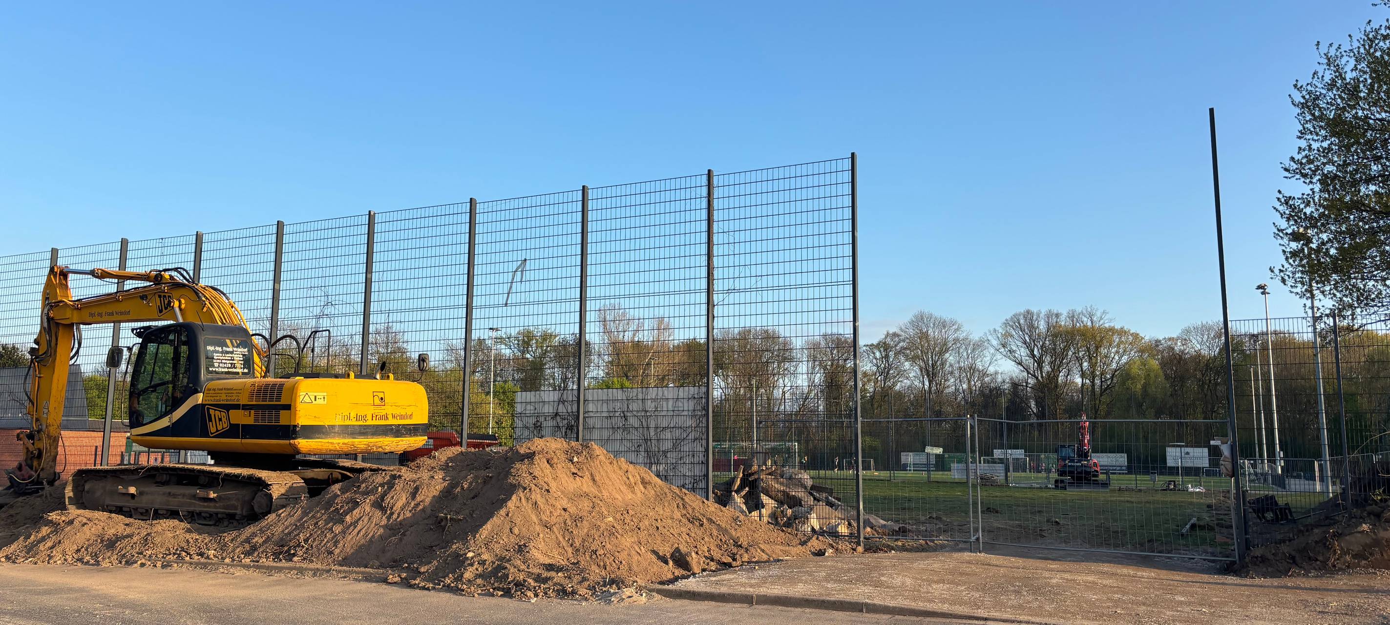 Ein gelber Bagger arbeitet auf der Anlage des SV Lohausen.