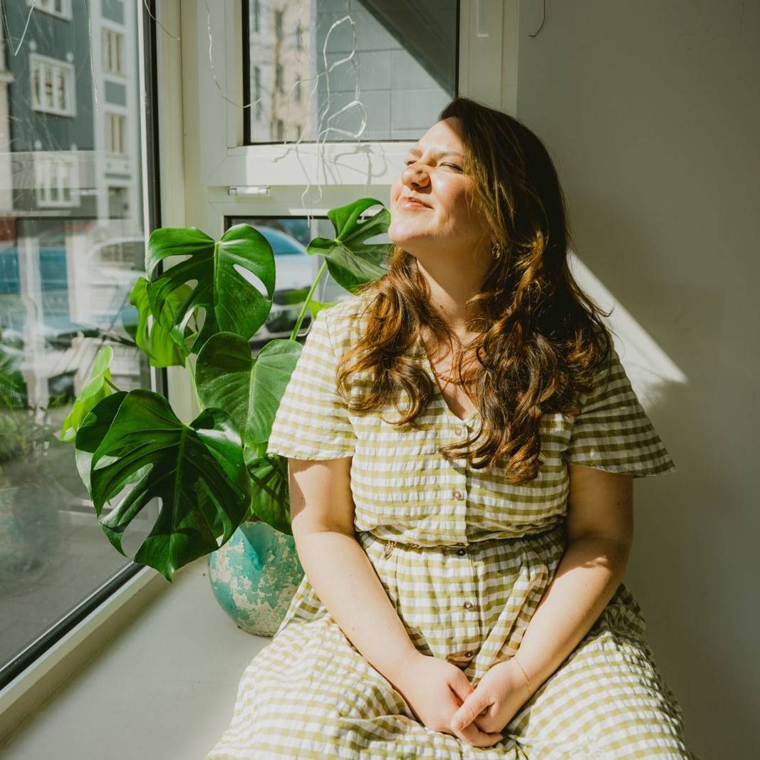 "Dus ist Liebe"-Gründerin Leni Janik sitzt auf einer Fensterbank in der Sonne.