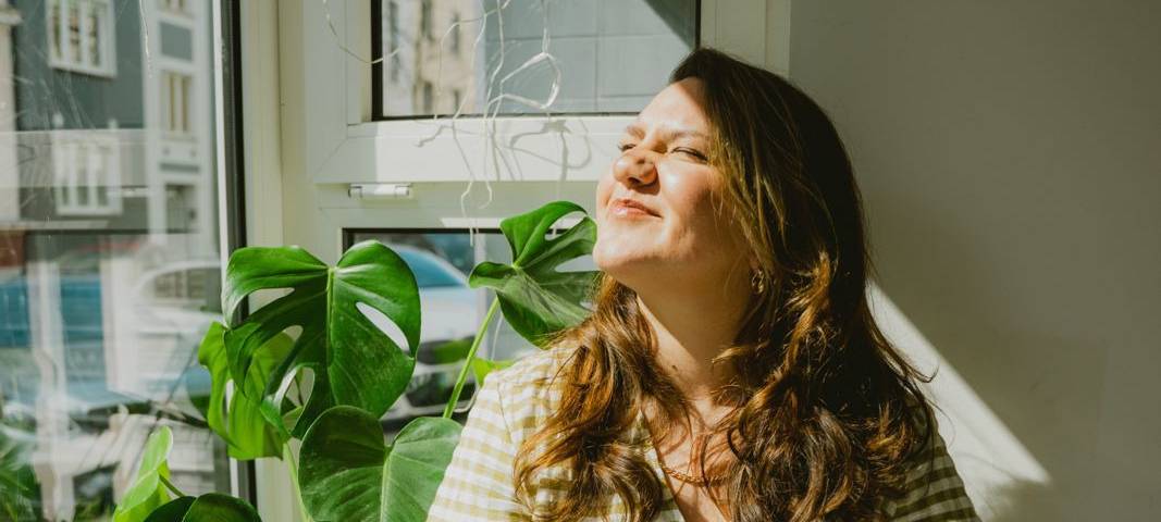 "Dus ist Liebe"-Gründerin Leni Janik sitzt auf einer Fensterbank in der Sonne.