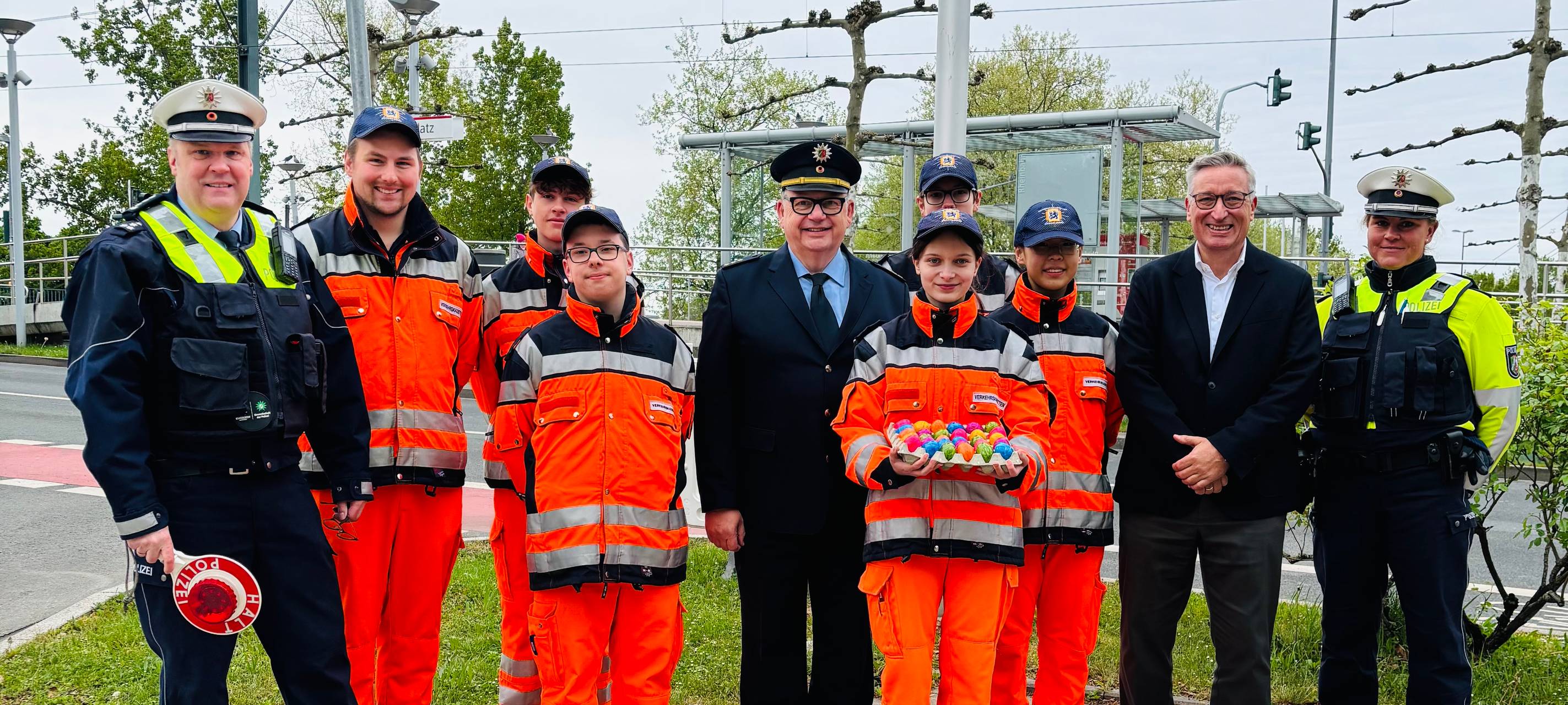 Mitarbeiterinnen und Mitarbeiter der Polizei und der Verkehrswacht Düsseldorf stehen an einer Straße mit Ostereiern in der Hand.