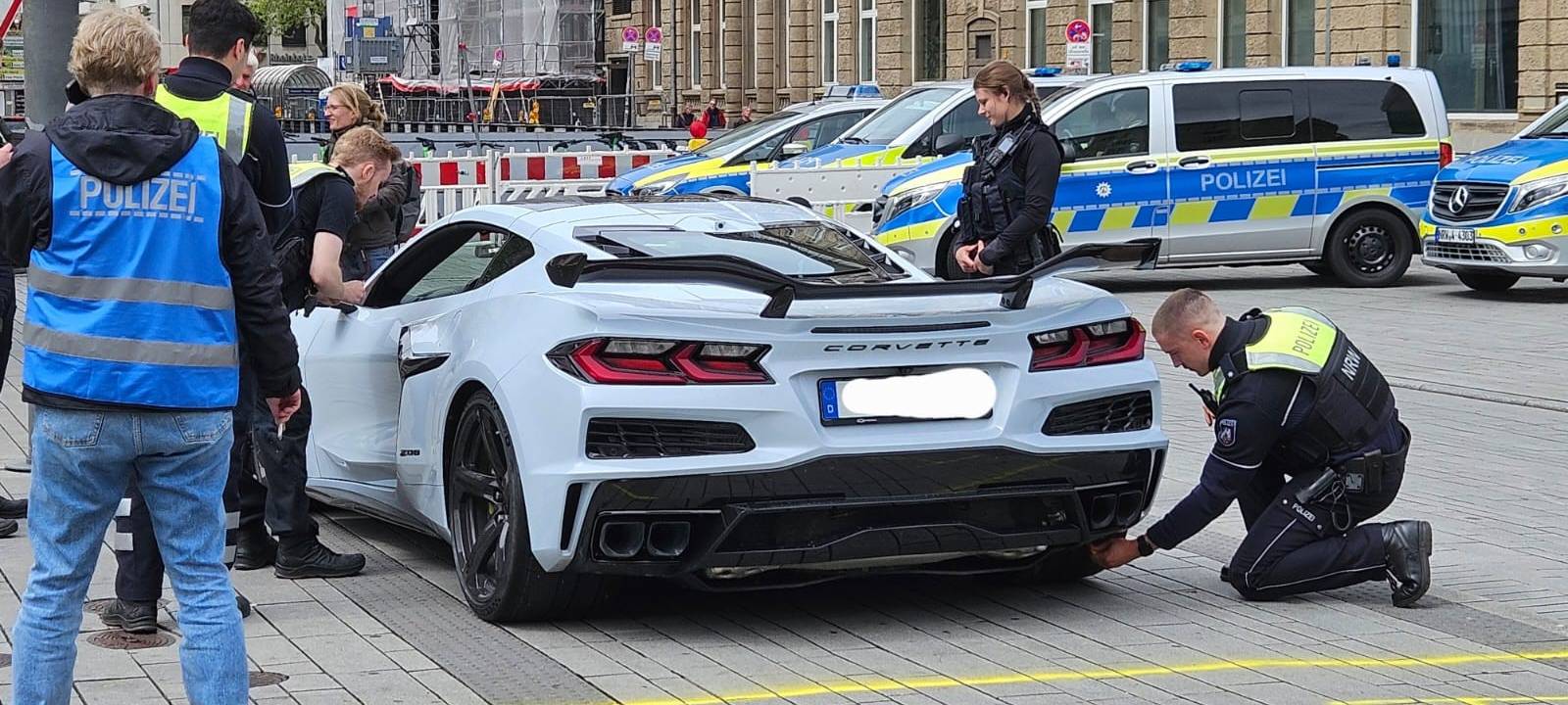 Mehrere Polizisten kontrollieren am Car-Freitag einen hellblauen Sportwagen.