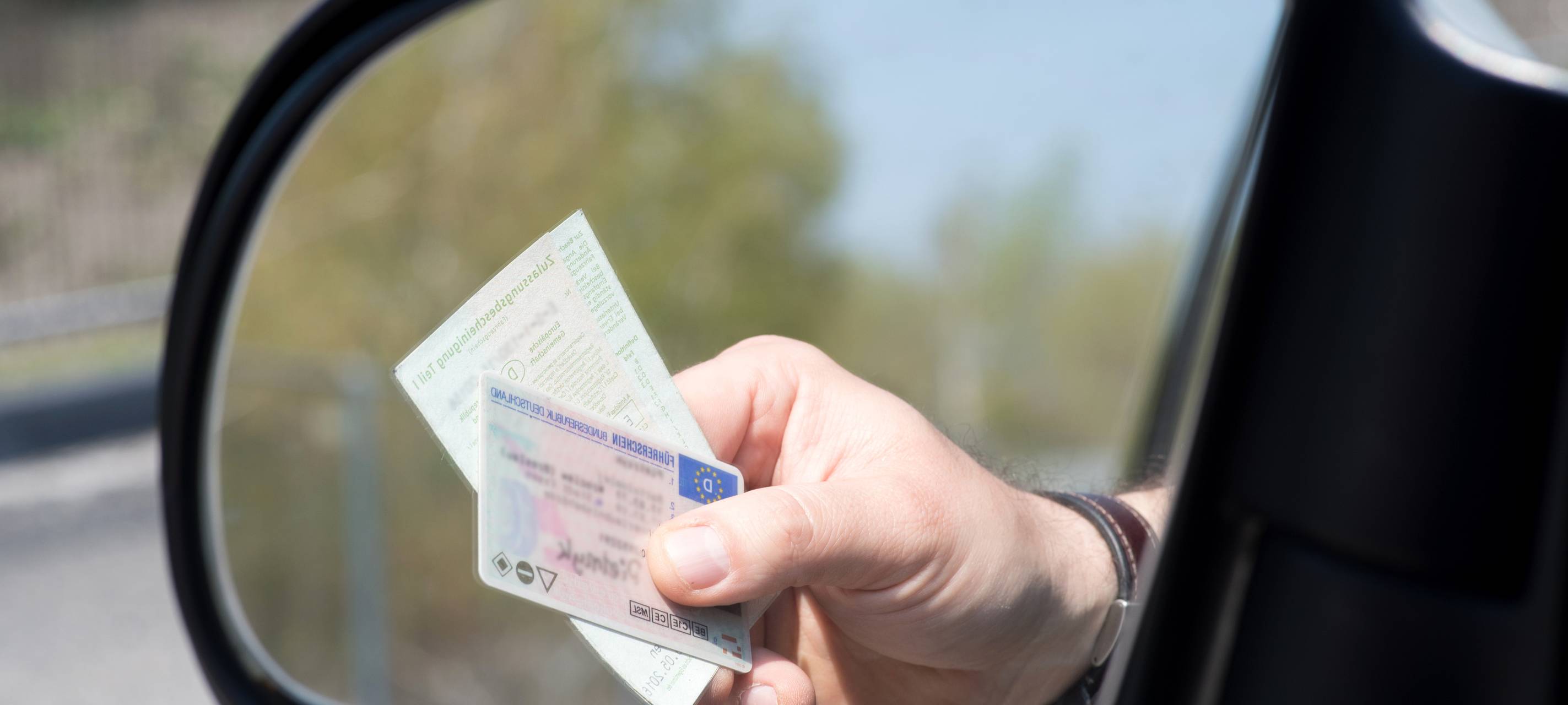 Ein Mann zeigt Führerschein und Fahrzeugschein bei einer Kontrolle der Polizei.