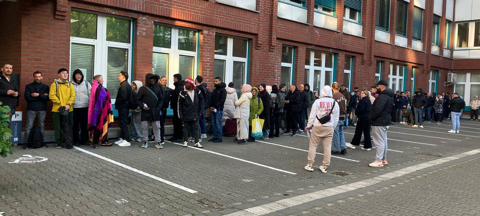 Menschen warten vor der Ausländerbehörde auf der Erkrather Straße.