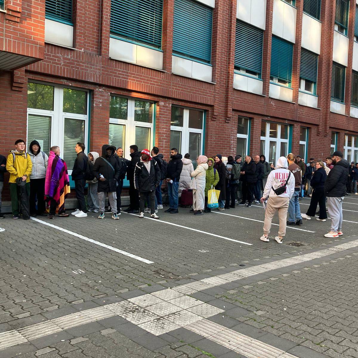 Menschen warten vor der Ausländerbehörde auf der Erkrather Straße.