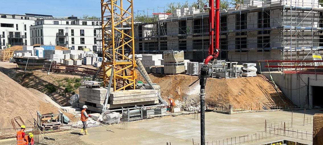 Die Bodenplatten des vierten Wohngebäudes der "Paulshöfe" in Düsseldorf-Benrath werden von Arbeitern gegossen.