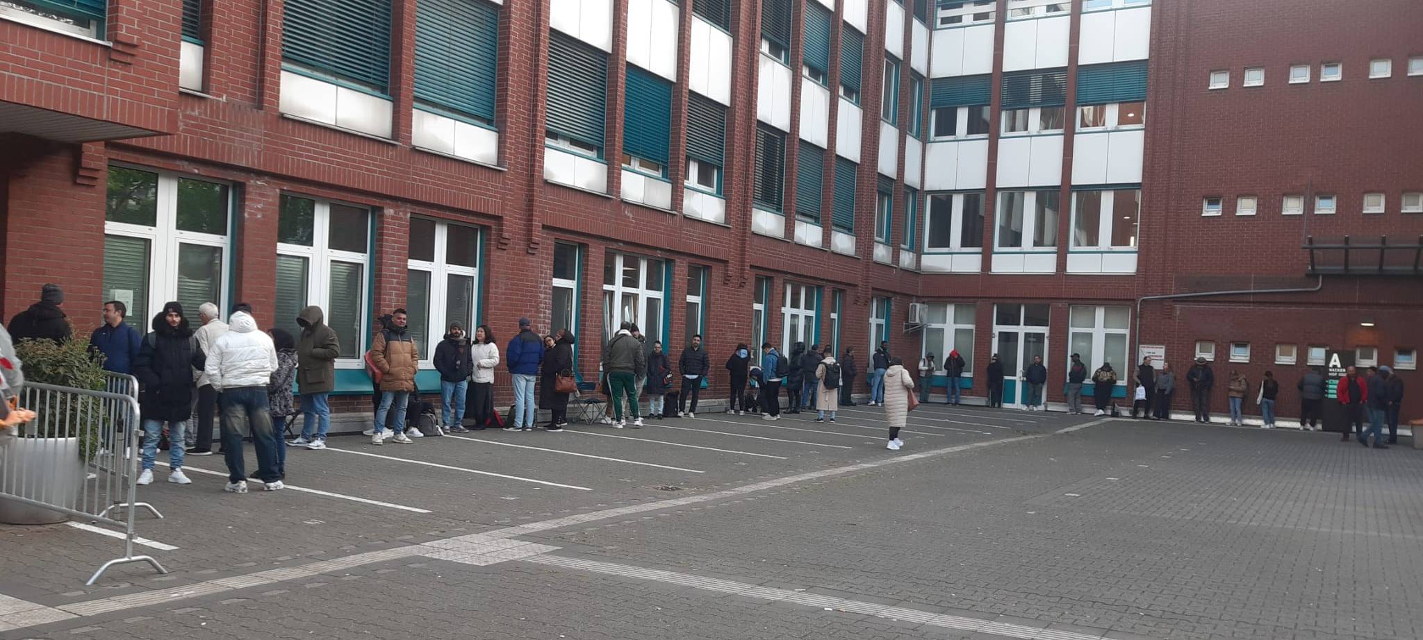 Menschen warten vor der Ausländerbehörde auf der Erkrather Straße.