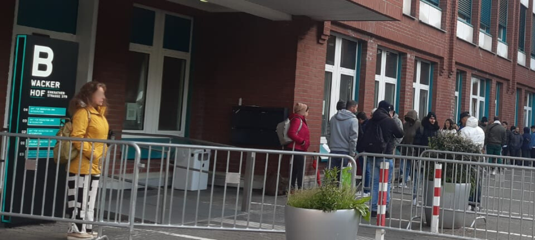 Menschen warten vor der Ausländerbehörde an der Erkrather Straße.