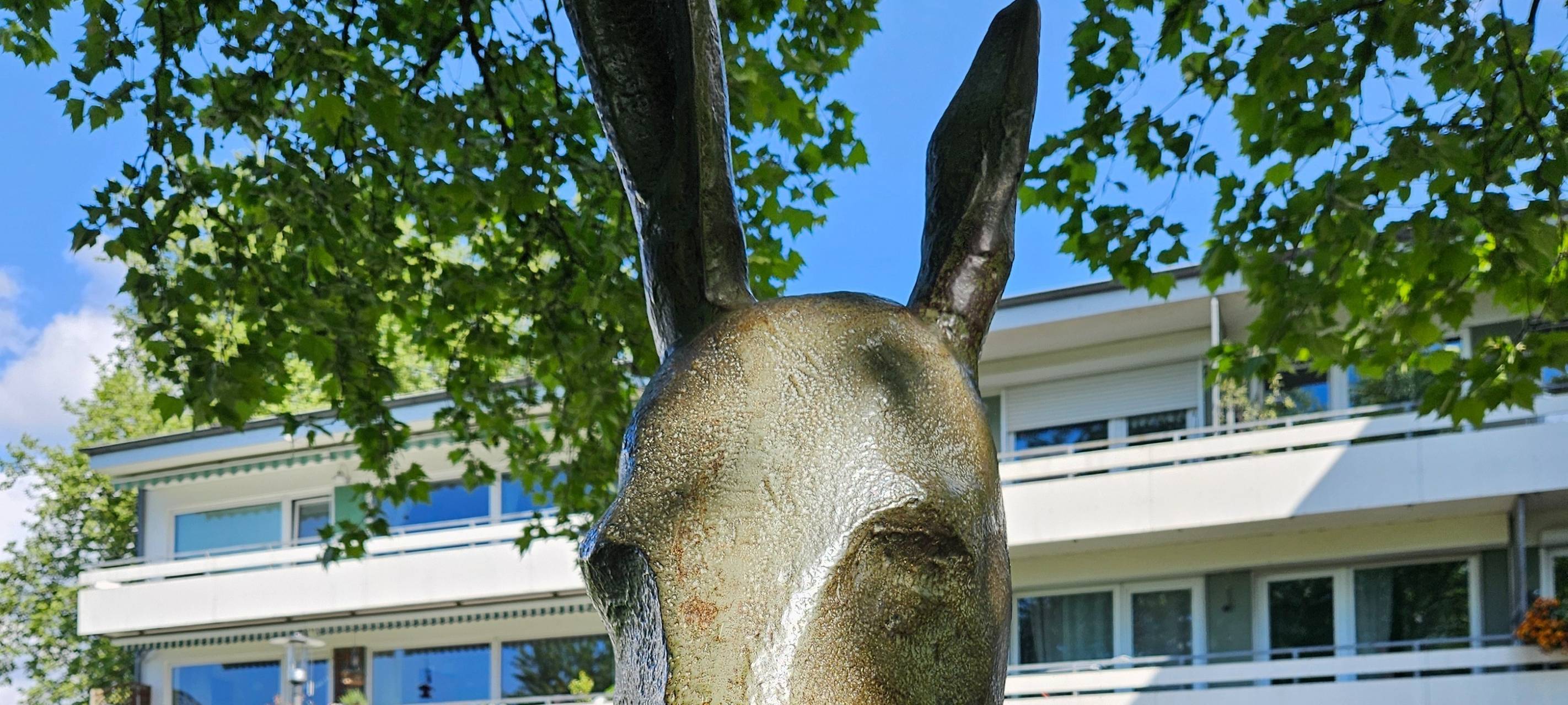 Esel Statue am Breidenplatz wird interviewt und ist umrahmt von Bäumen und Sträuchern