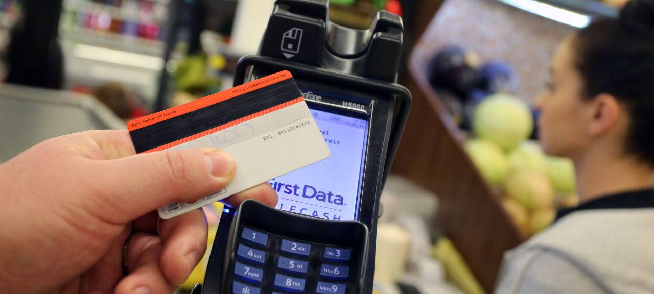 Eine Karte wird an den Bezahl-Terminal an der Kasse eines Supermarktes gehalten