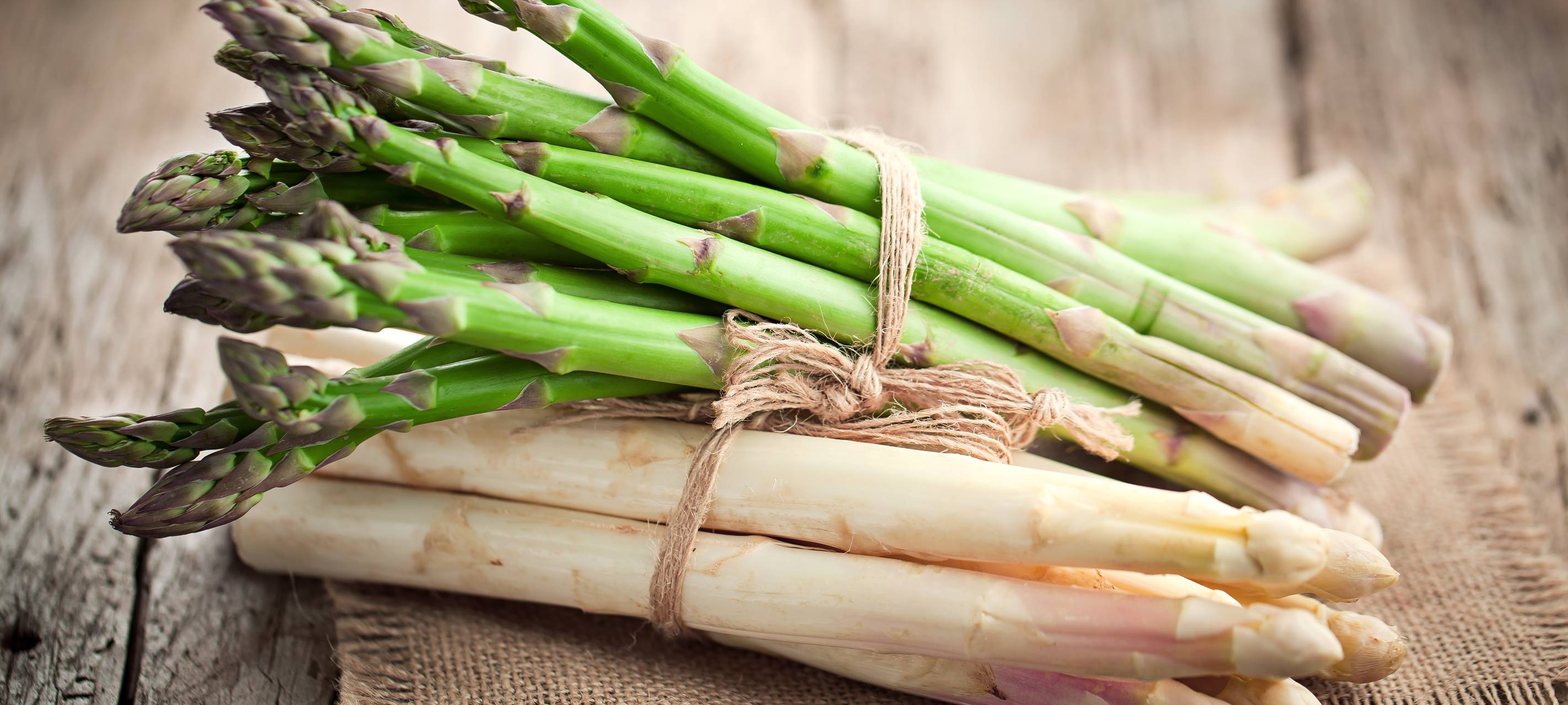Grüner und weißer Spargel auf einem Holzbrett.