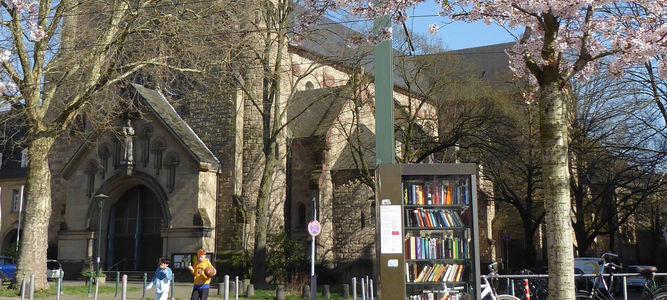 Im Vordergrund ein offenes Bücherregal, im Hintergrund die Kirche St. Antonius Friedrichstadt