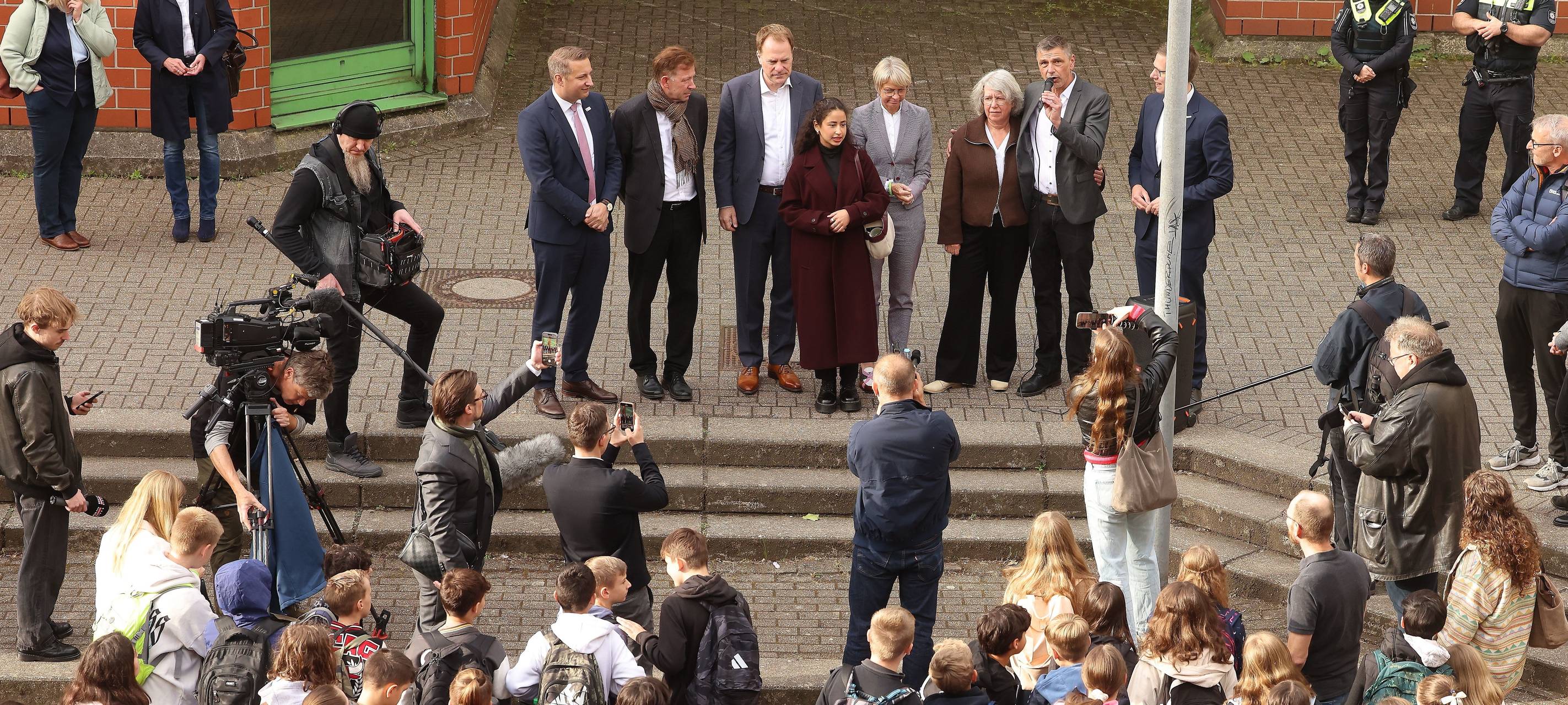 OB Keller und Vertreter der Schulen und des Landes eröffnen die provisorische Heimat der Erkrather Schulen in Benrath. Viele Schülerinnen und Schüler hören den Reden zu.