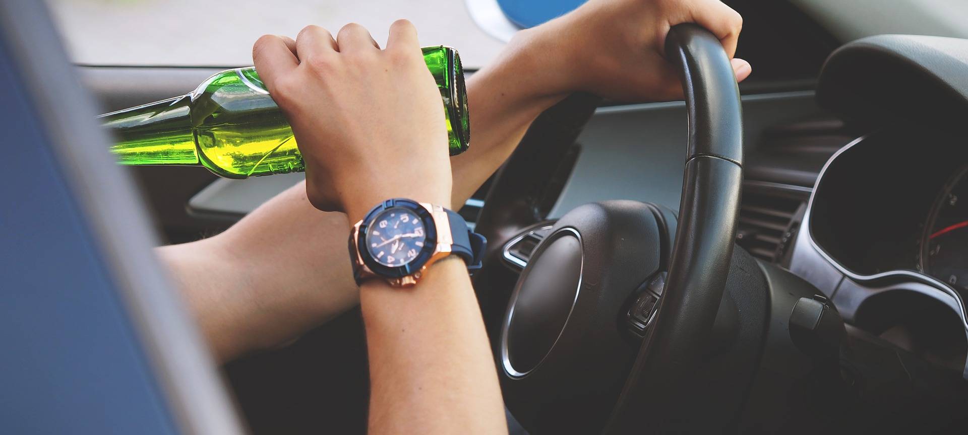 Ein Autofahrer trinkt Bier während der Fahrt