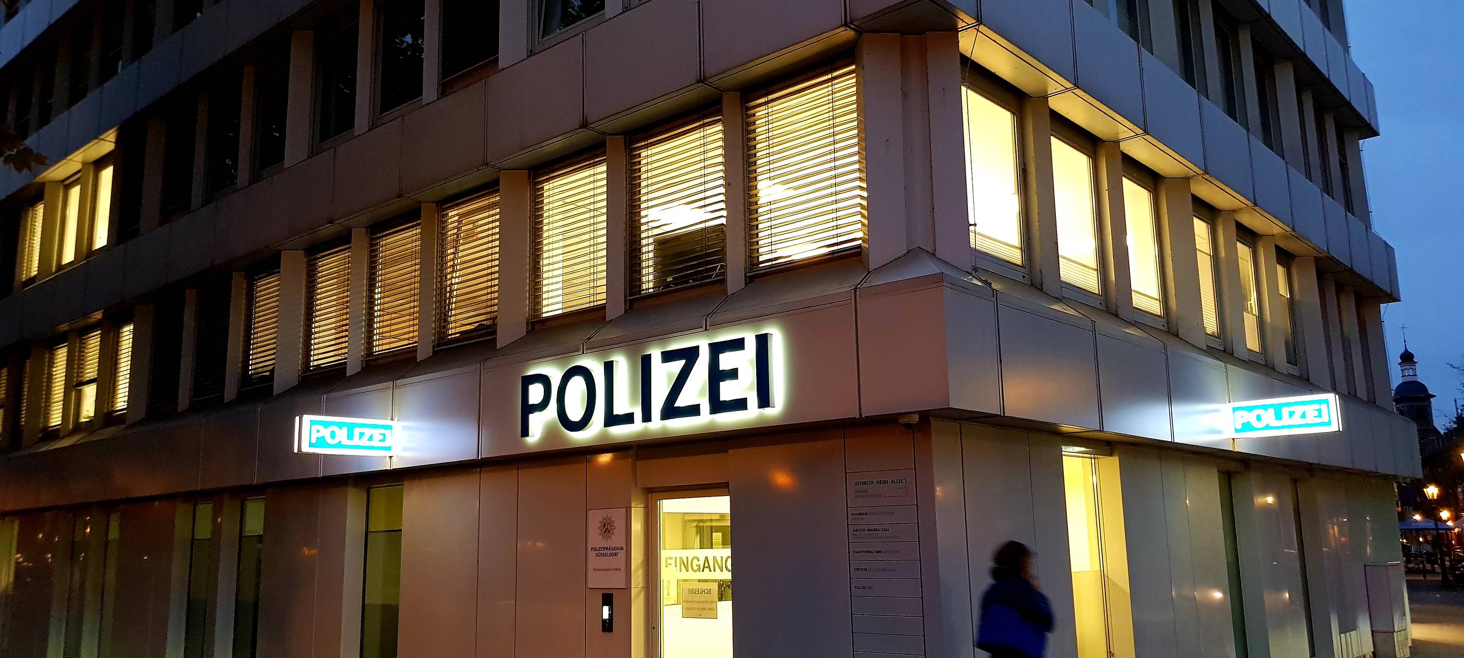 Außenansicht der beleuchteten Polizeiwache in der Düsseldorfer Altstadt bei Dunkelheit.