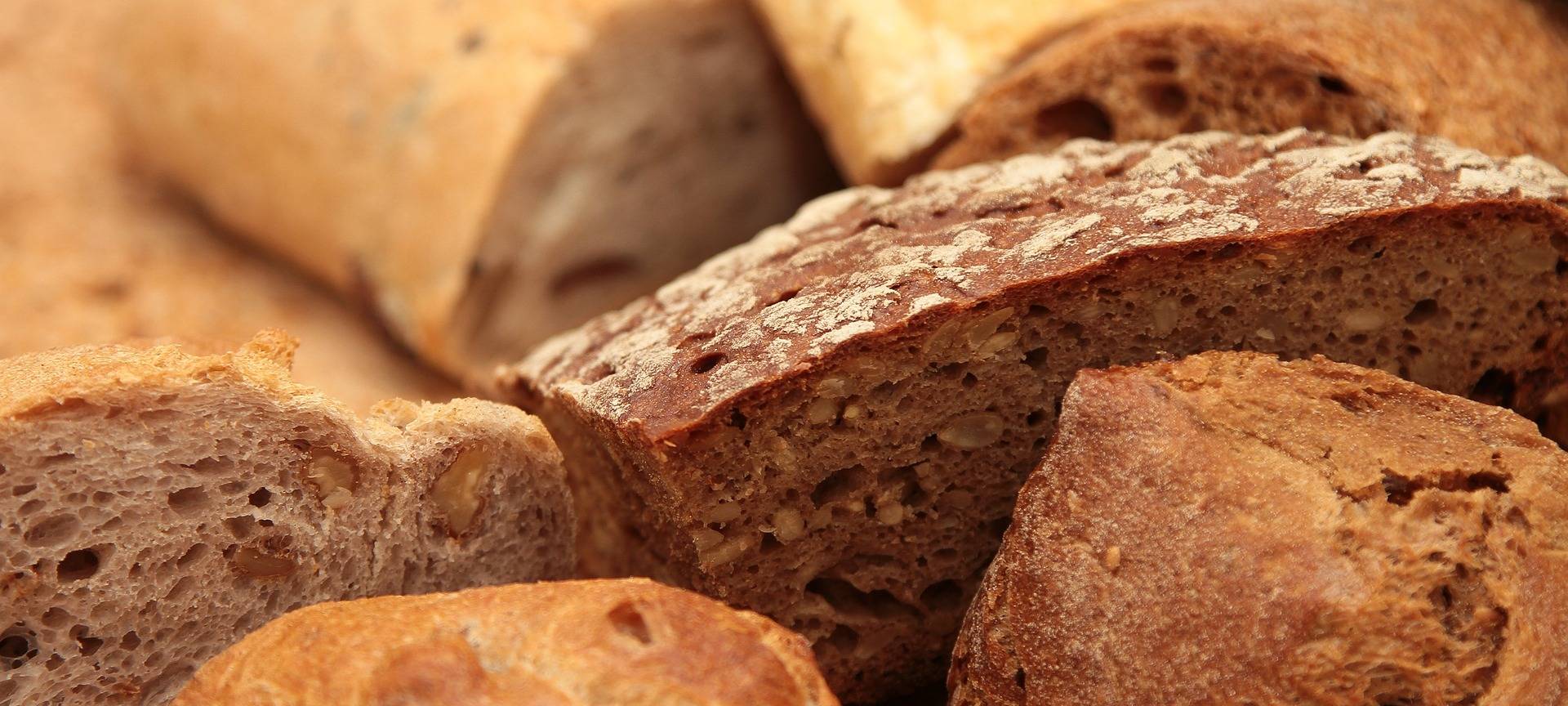 Brote und Brötchen liegen auf einer Holzplatte.