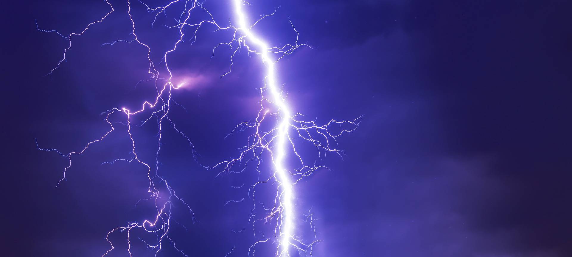 Ein heller Blitz vor einem stark bewölkten Nachthimmel