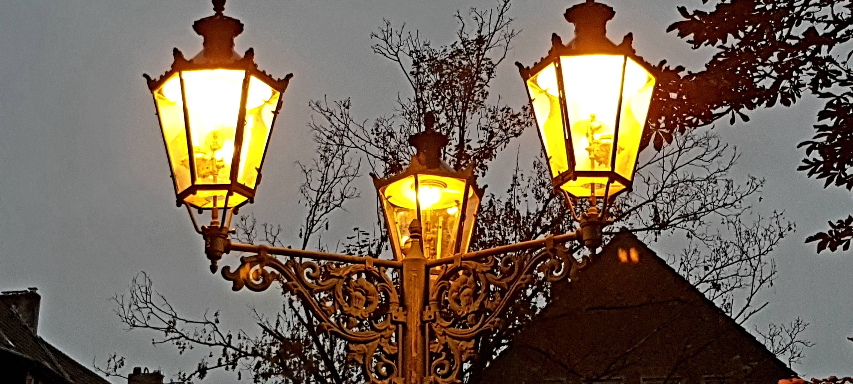 Drei Gaslaternen leuchten in der Dämmerung