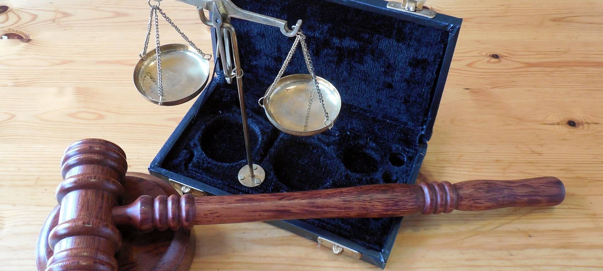 Eine kleine Waage und ein Gerichtshammer. Symbole, die für ein Gericht stehen.