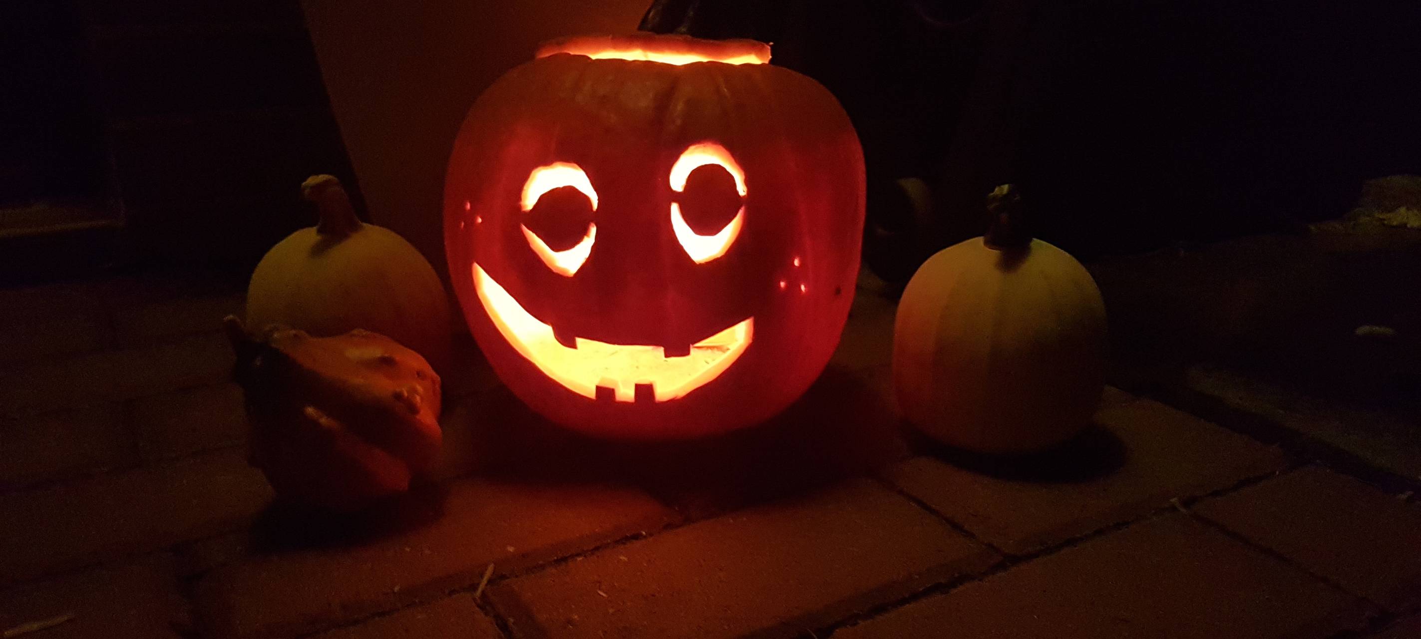 Ein geschnitzter Halloween-Kürbis. Eine Kerze im Inneren beleuchtet den Kürbis mit seiner Grimasse.