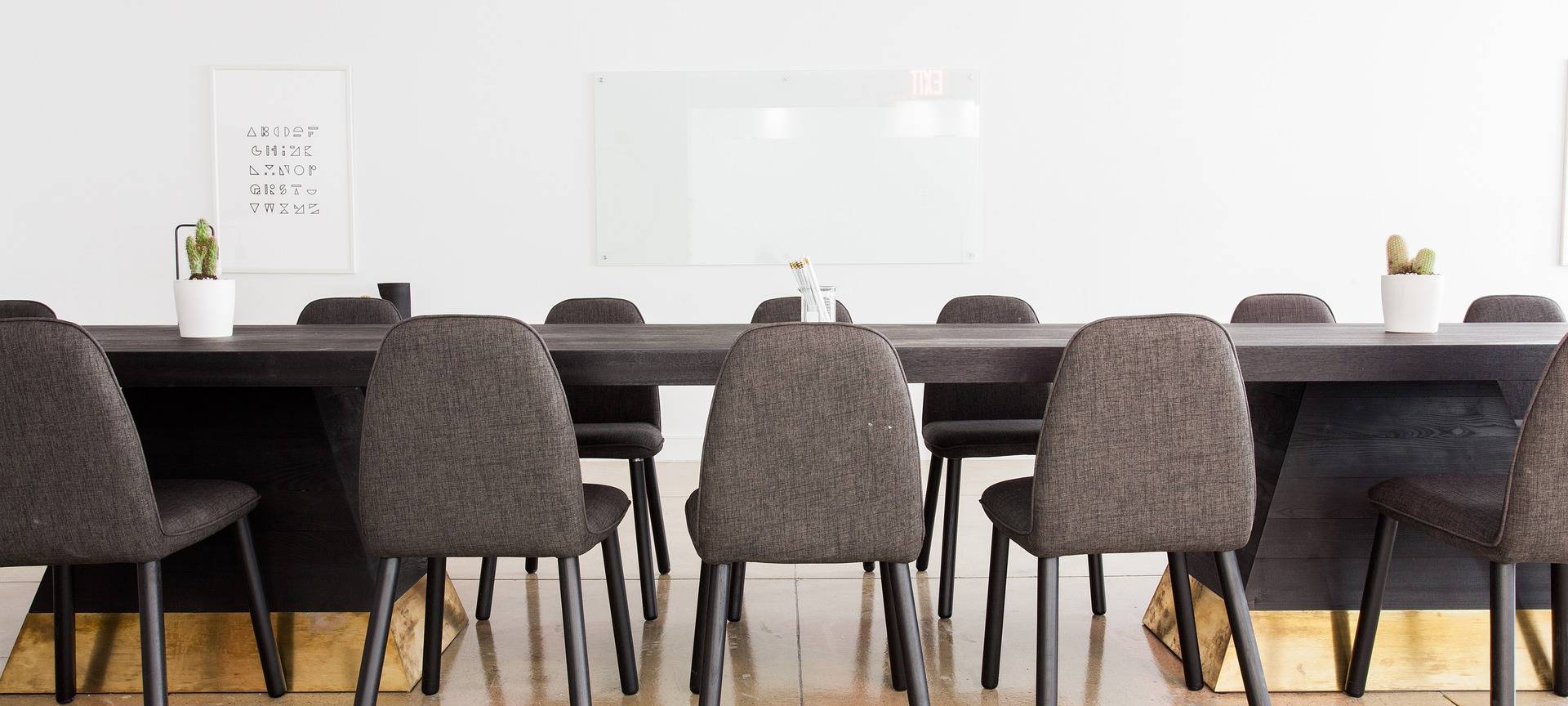 Graue Stühle stehen an einem Konferenztisch in einem leeren Büro.