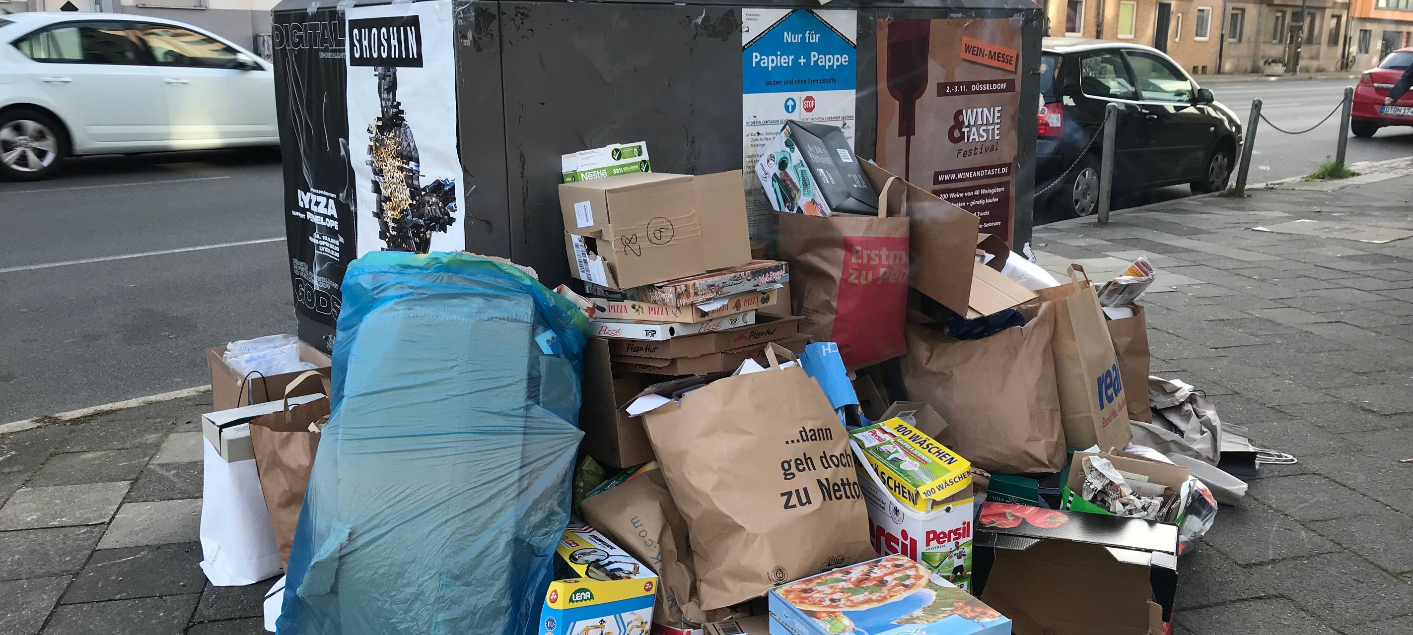 Müll liegt vor einem Müllcontainer.