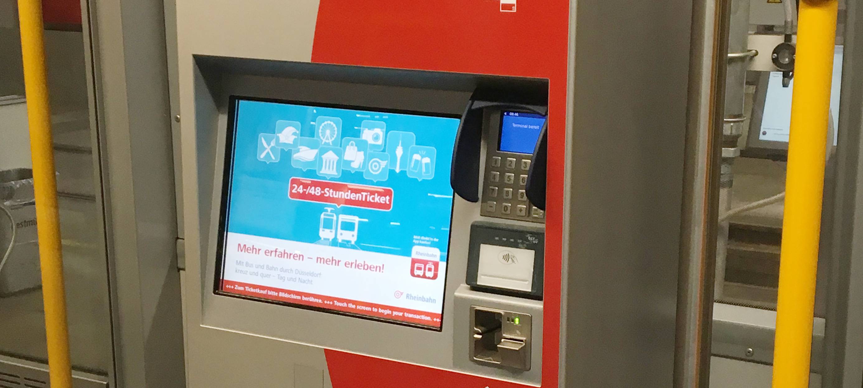 Ein rot-grauer Ticketautomat der Rheinbahn in einer Straßenbahn.