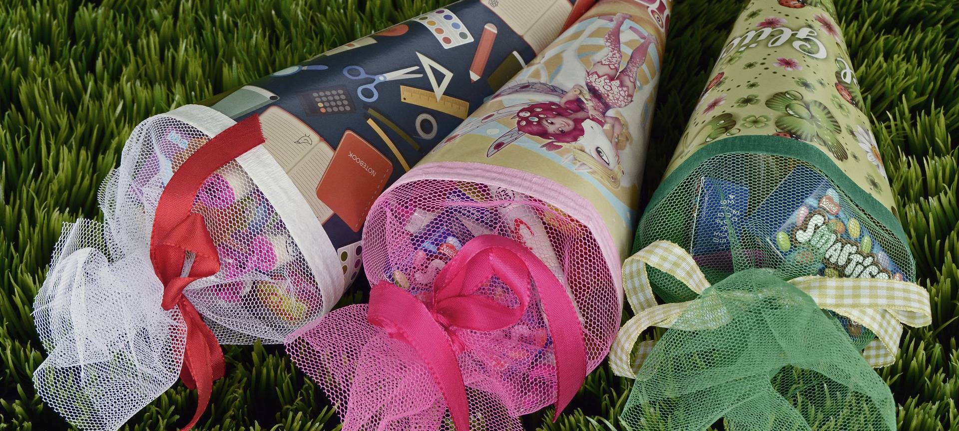 Drei Schultüten liegen fertig gepackt auf einer Wiese