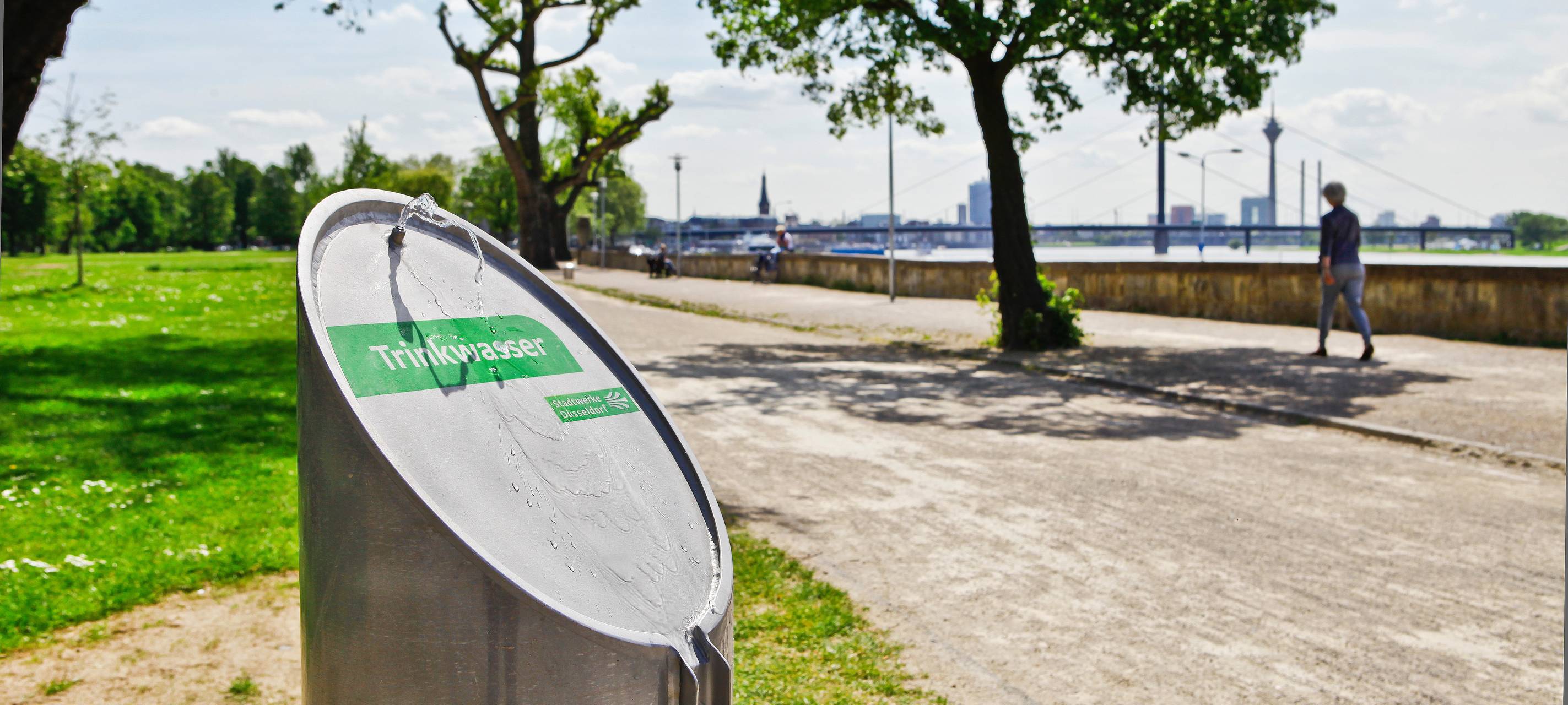 Ein Trinkwasserbrunnen von den Stadtwerken Düsseldorf im Rheinpark in Golzheim. Im Hintergrund ist der Rhein zusehen.