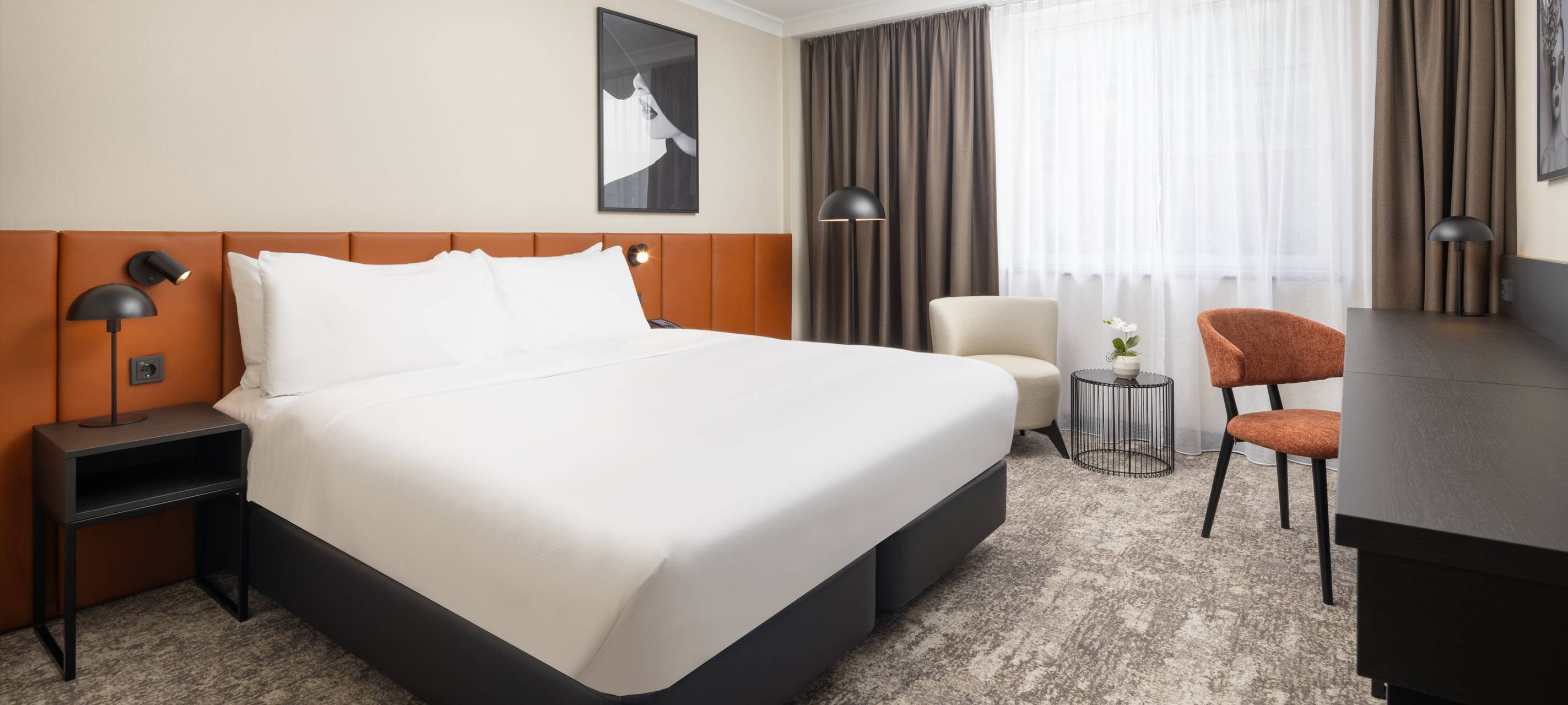 Eine Aufnahme von einem neugestalteten Gästezimmer im Hilton-Hotel mit großem Bett und großem Fenster.