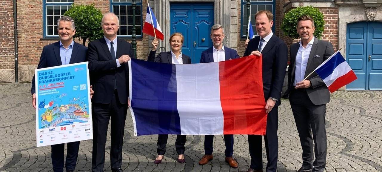 Ein Gruppenfoto vor dem Düsseldorfer Rathaus mit Frankreich-Fahne zum Frankreichfest