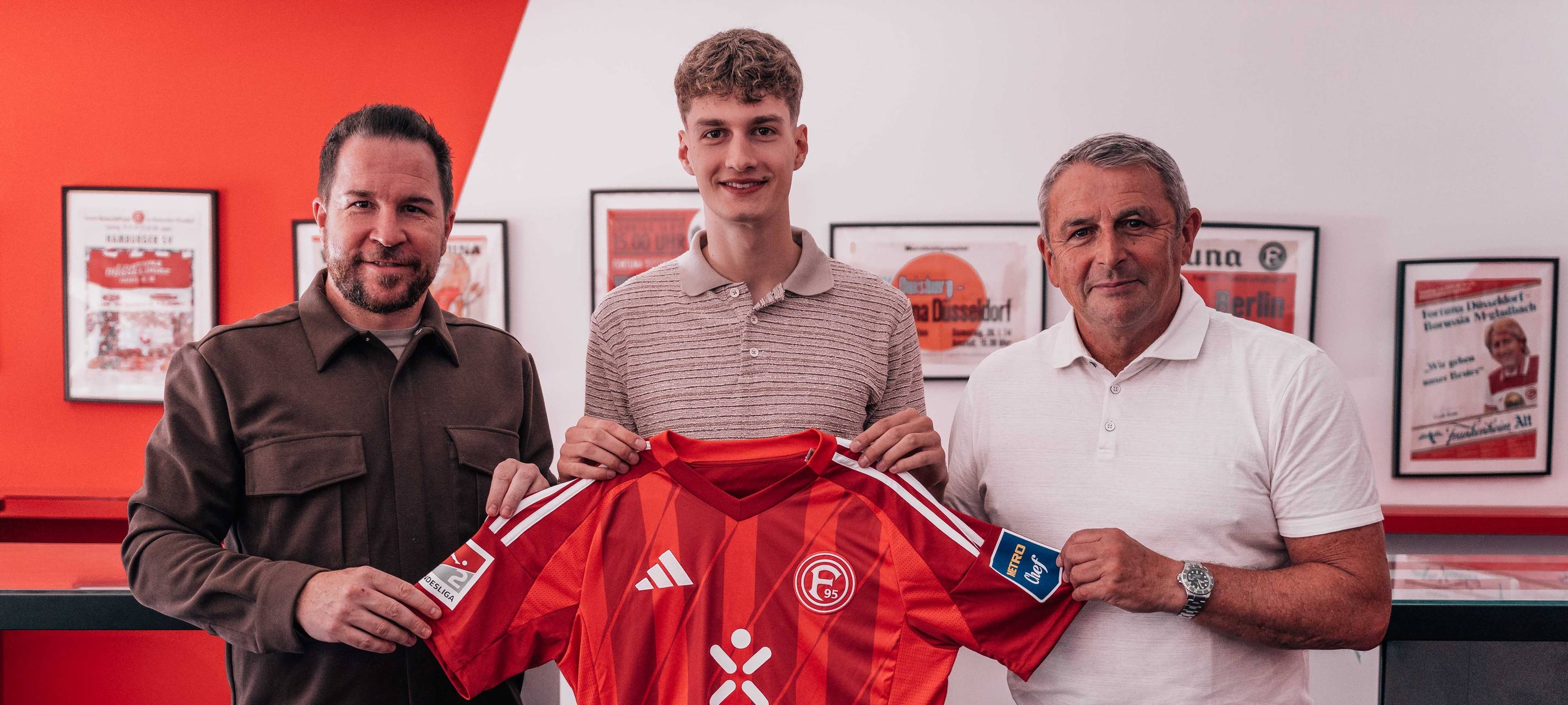 Der Spieler Luca Raimund hält das Trikot von Fortuna Düsseldorf hoch.