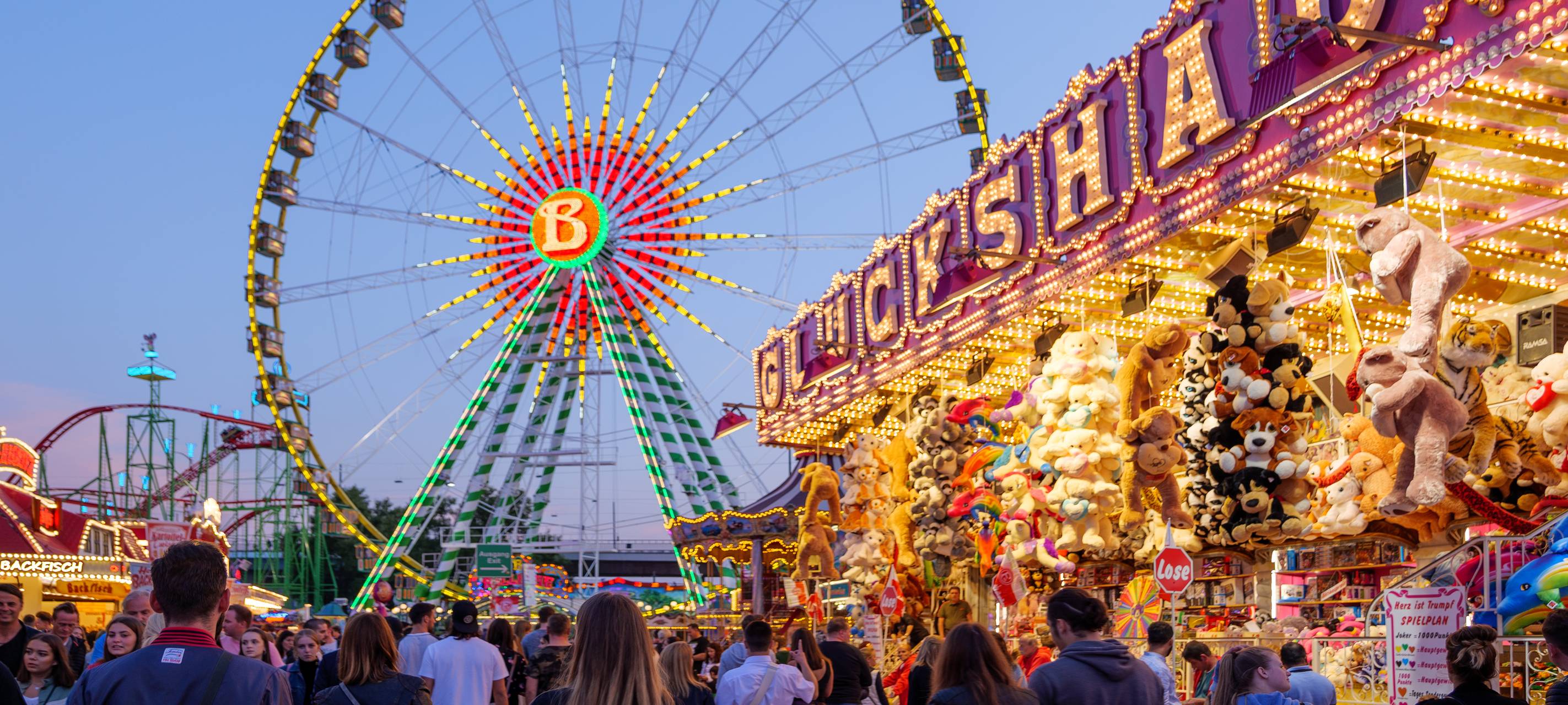 Die Düsseldorfer Rheinkirmes bei Nacht. Mit Riesenrad und dem Glückhaus, einer Losbude.