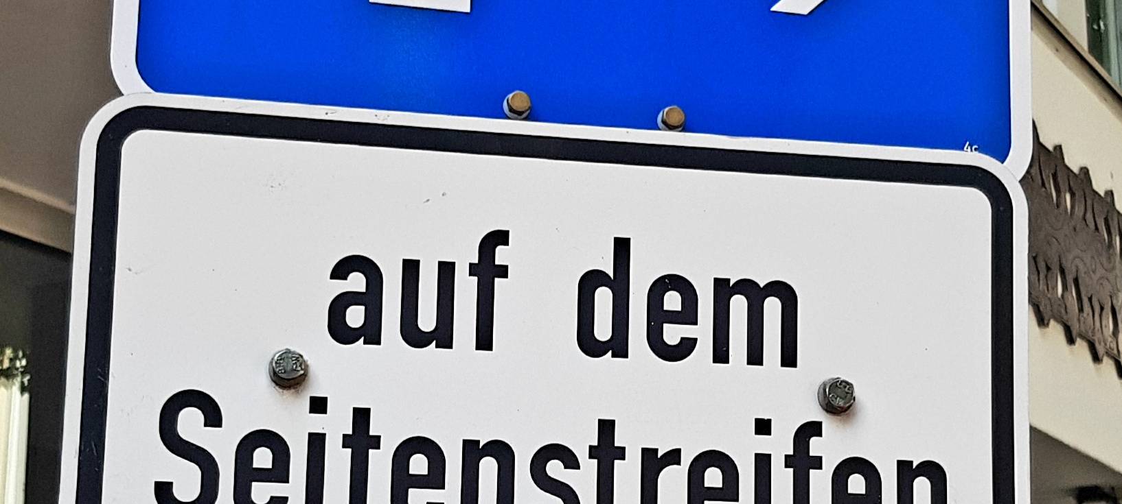 Ein blaues Schild, dass das Parken regelt. In diesem Fall geht um reservierte Plätze für Menschen mit Behinderungen.