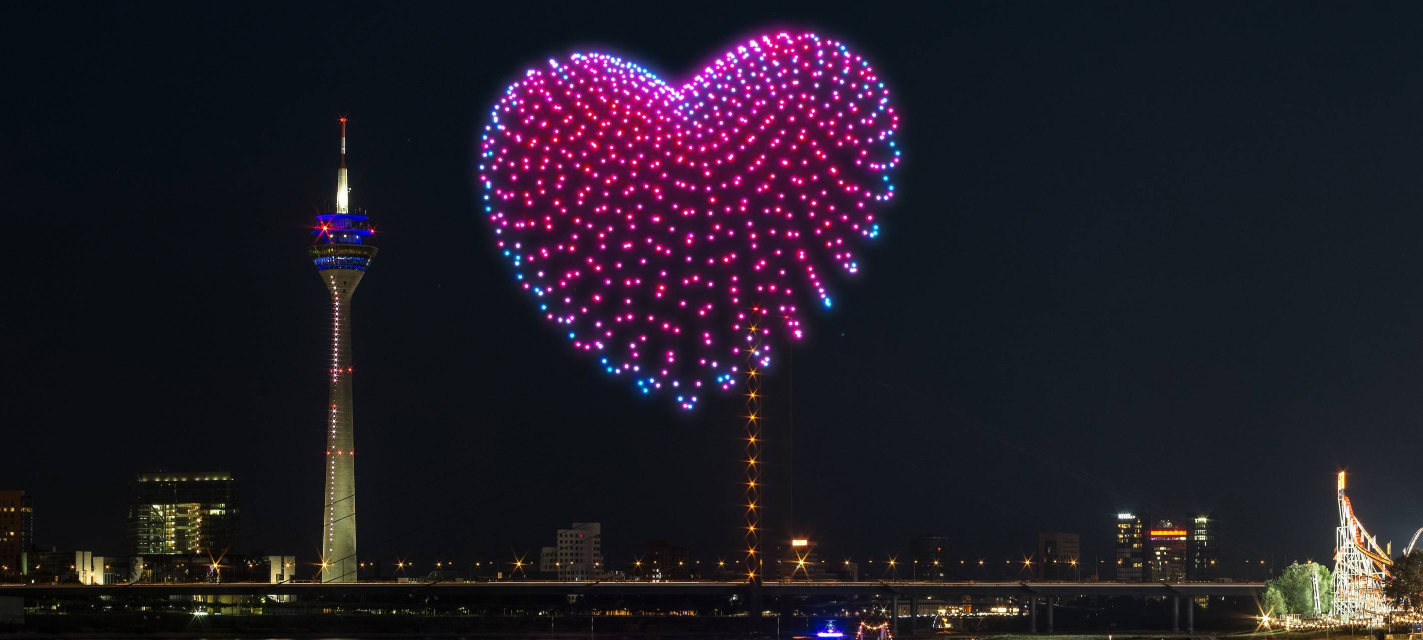 Eine Visualiesierung der Drohnenshow zur Rheinkirmes. Drohnen malen ein Herz in den Himmel. So wird es auch bei der Rheinkirmes 2026 aussehen.