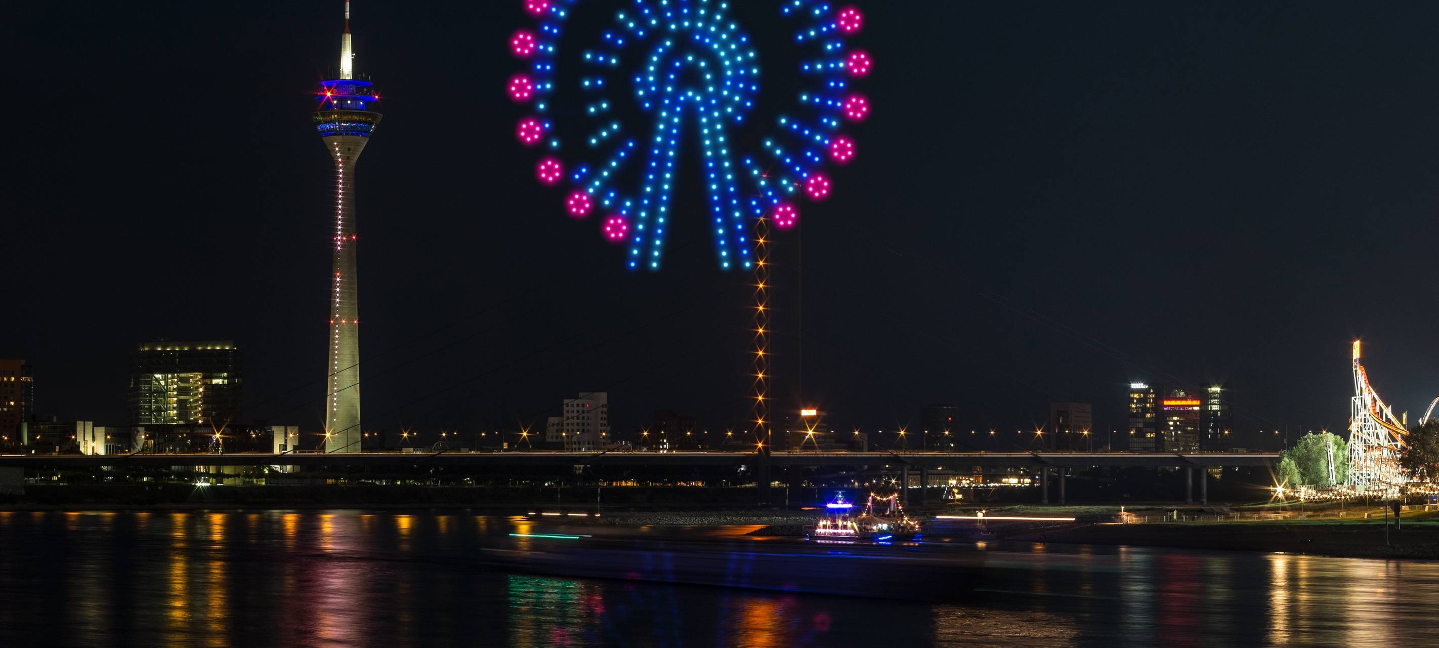 Eine Visualiesierung der Drohnenshow zur Rheinkirmes. Drohnen malen ein Risenrad in den Himmel.