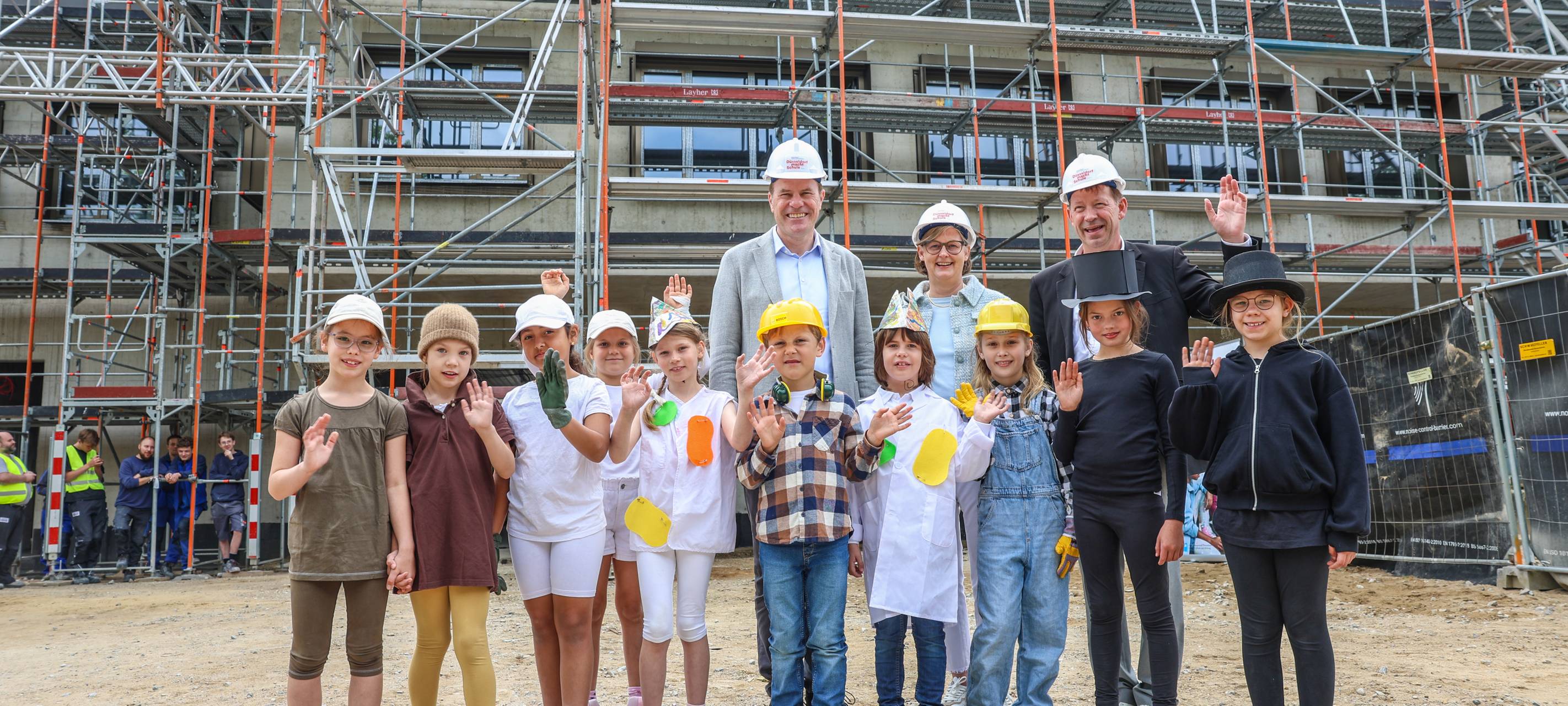 Beim Richtfest: Oberbürgermeister Dr. Stephan Keller, komm. Schulleiterin Susanne Schulz-Isenbeck und Stadtdirektor Burkhard Hintzsche mit Schülerinnen und Schülern der 2a.