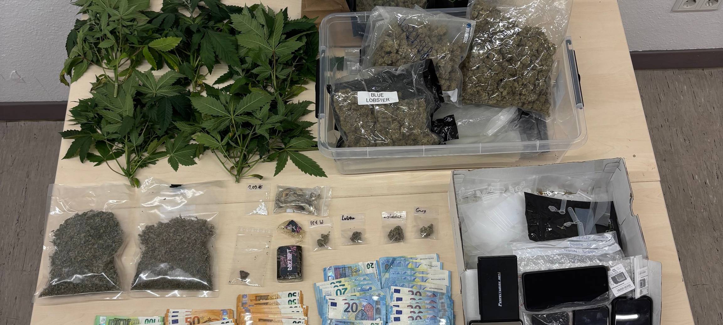 Drogen, andere Betäubungsmittel und über 20.000€ Bargeld liegen nebeneinander auf einem Brett bei der Polizei. Die vielen Geldscheine reichen von 5€ bis 200€.