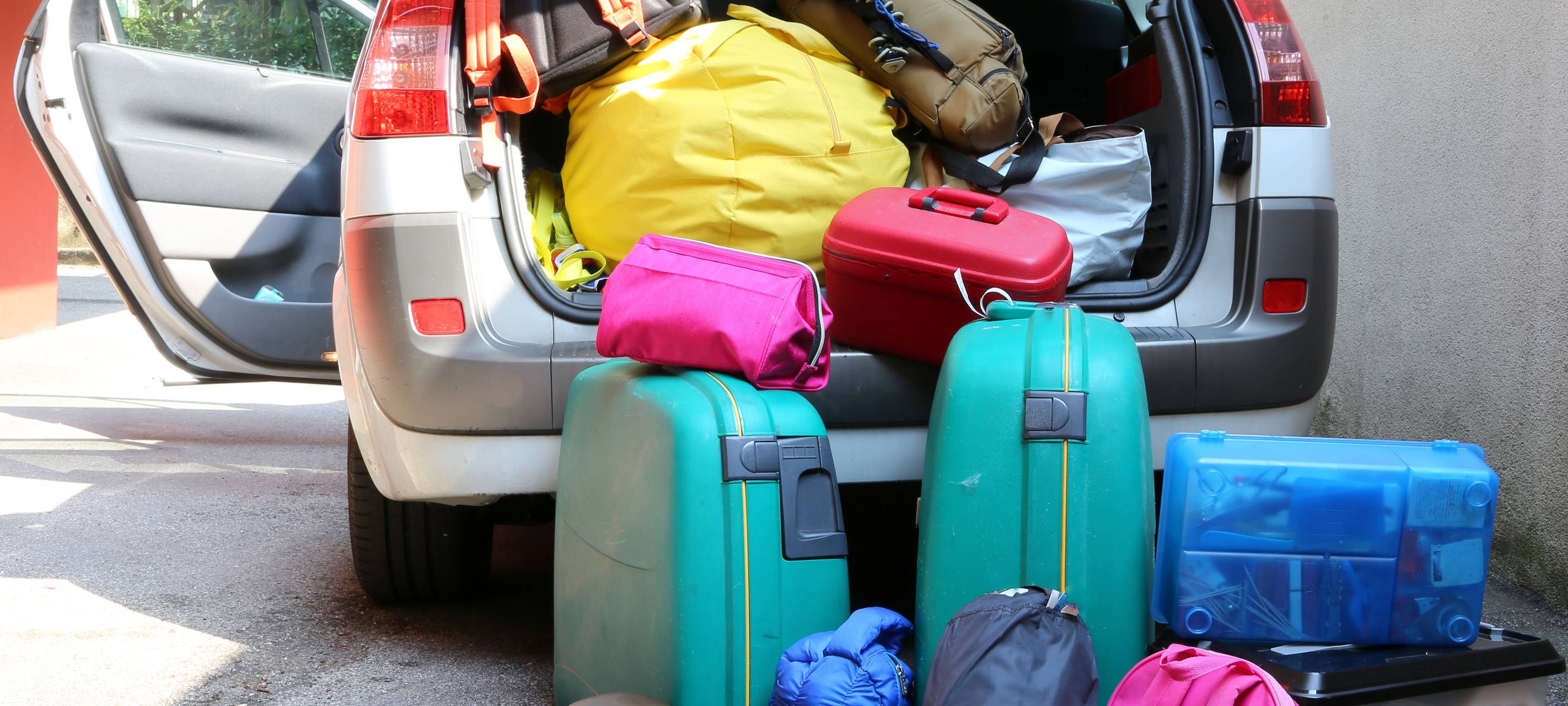 Ein Auto, überladen mit Koffern und Reisetaschen für eine Familienreise.