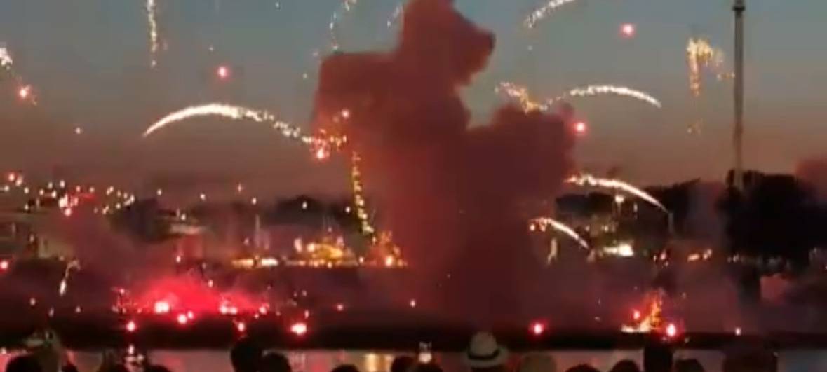 Mehrere Menschen stehen am Mannesmannufer und beobachten das Feuerwerk. Auf der anderen Rheinseite sieht man, wie ein Feuerwerkskörper sehr niedrig explodiert ist.