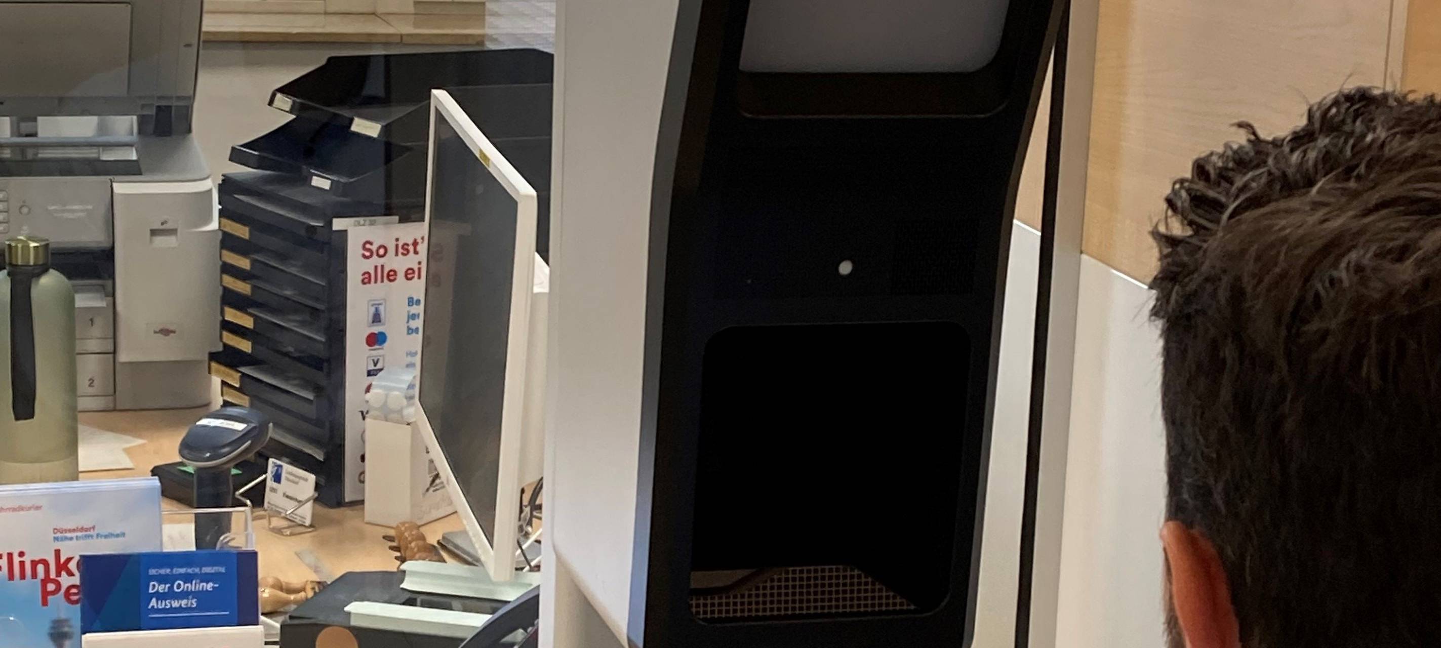 Auf einem Schreibtisch in einem Düsseldorfer Bürgerbüro steht ein Foto-Terminal. Hier können wir digitale Passbilder machen lassen.