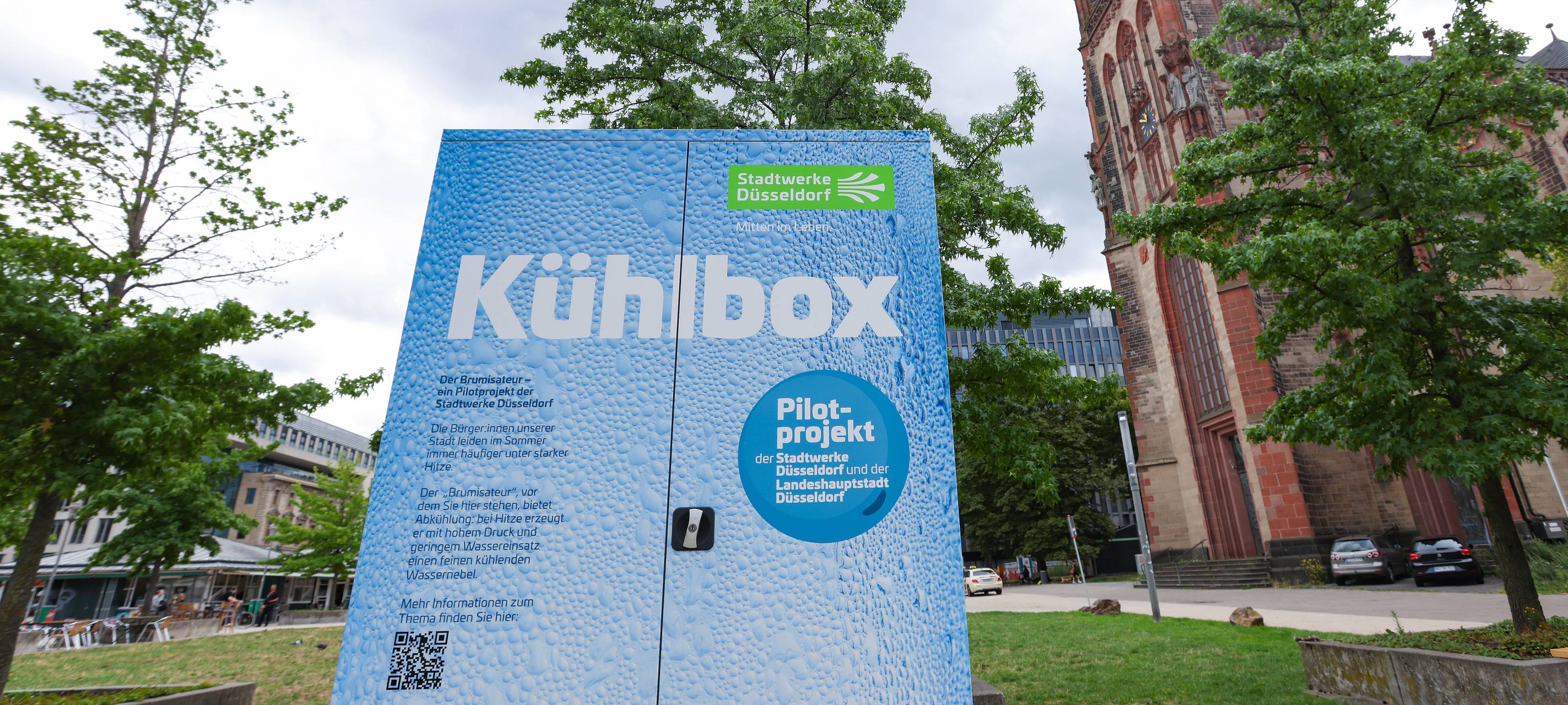 Eine große Kühlbox, genannt Brumisateur, steht auf dem Kirchplatz - ein Pilotprojekt zur Stadtabkühlung von Stadt und Stadtwerke.