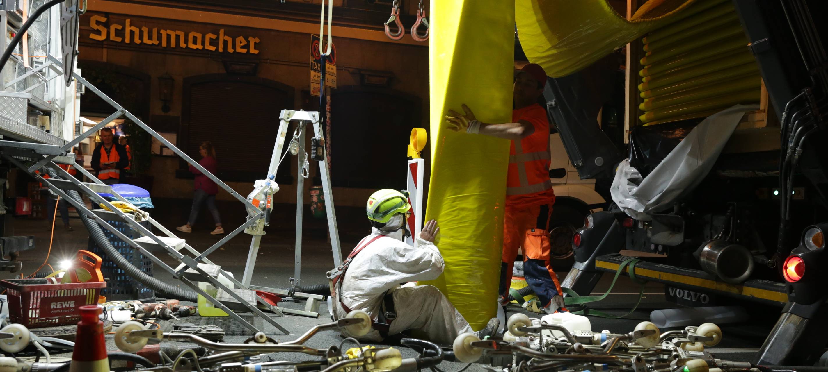 Der Stadtentwässerungsbetrieb hat den Kanal an der Oststraße saniert. Hier ist der Einzug des "Inliners" zu sehen. Zwei Männer in weißen und orangenen Schutzjacken führen den gelben Schlauch in den Kanal ein.