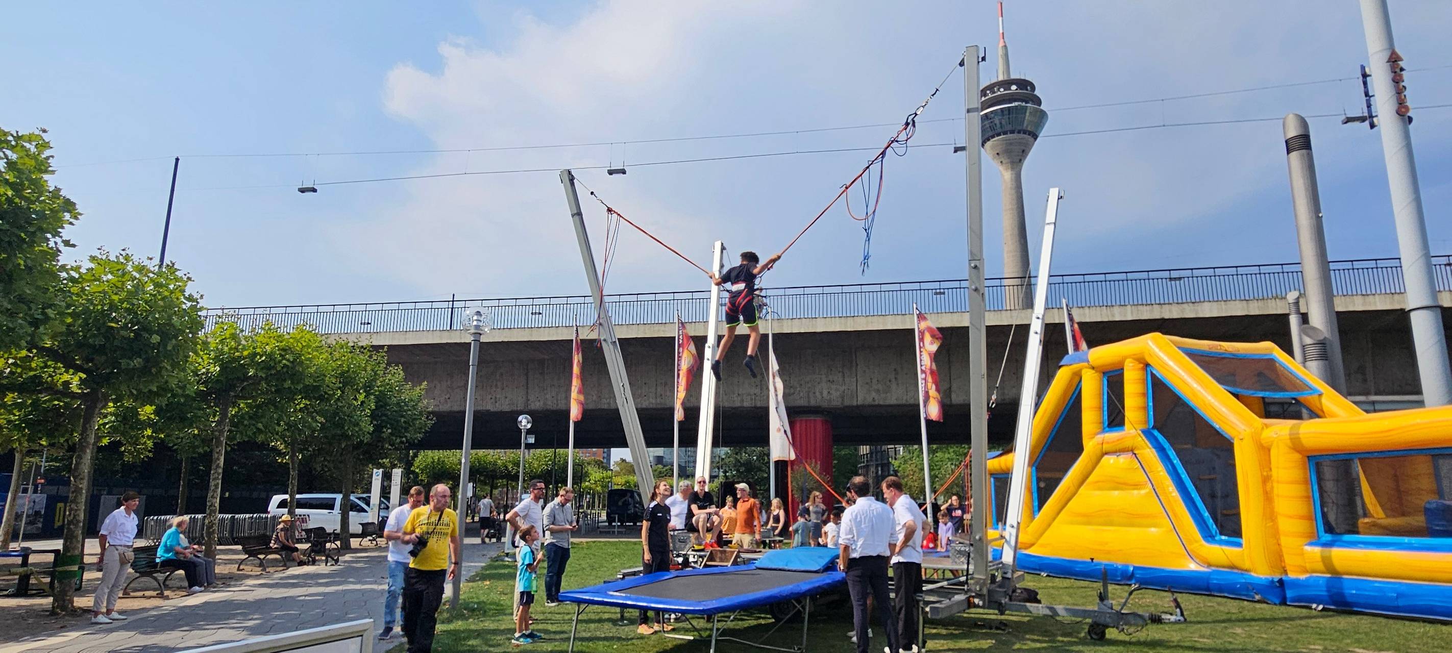 Olympic adventure Camp mit Hüpfburg, Trampolin und Aussicht auf den Rheinturm.