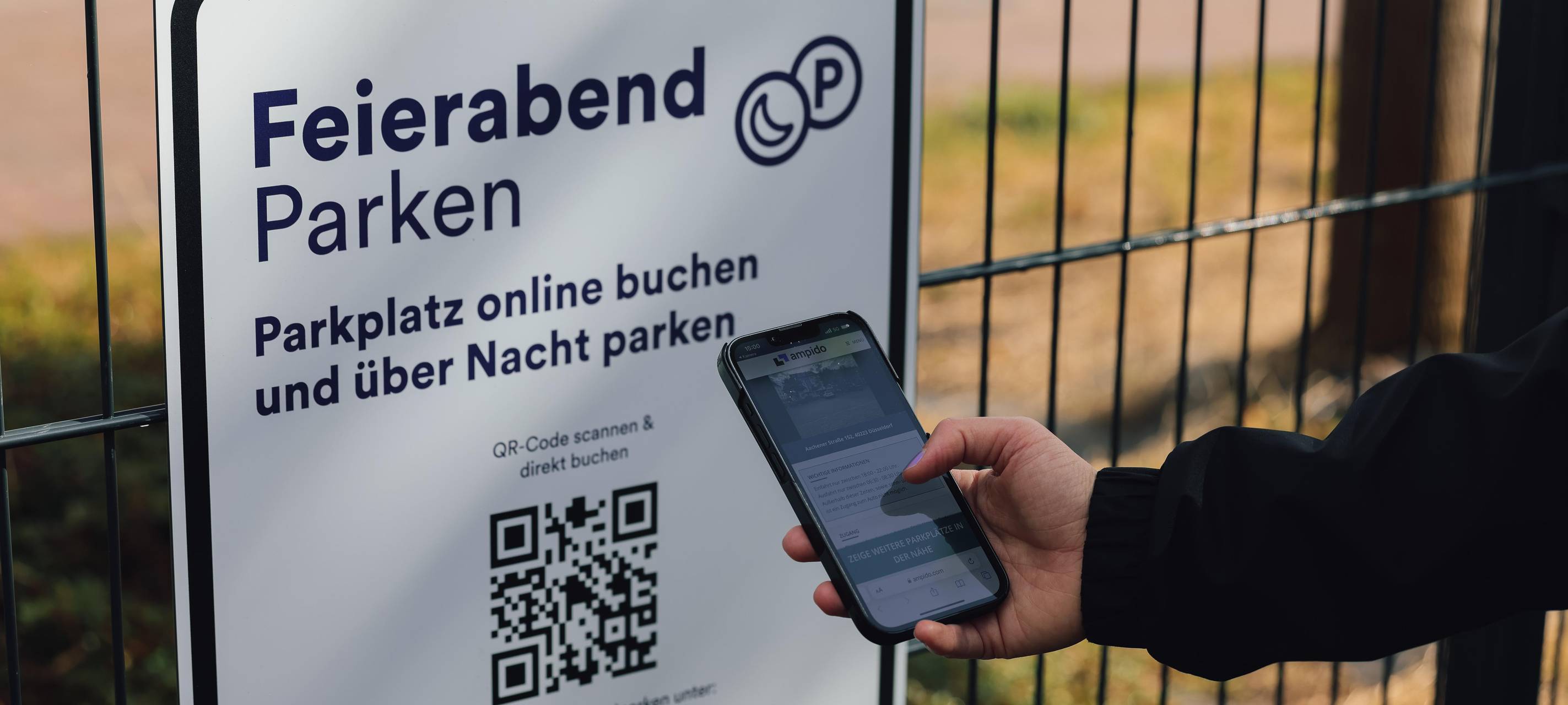 Mit seinem Smartphone in der hand scannt ein Mann den QR-Code auf dem Schild für das Feierabend-Parken.