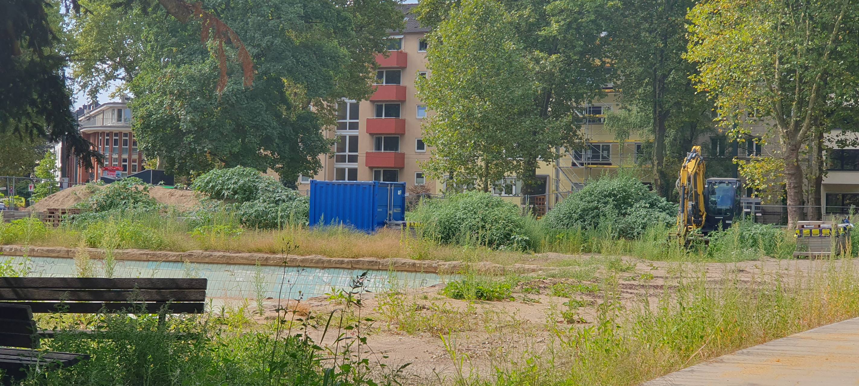 Baustelle auf dem Schillerplatz. Im Hintergrund steht ein gelber Bagger. Der Platz wirkt ungepflegt.