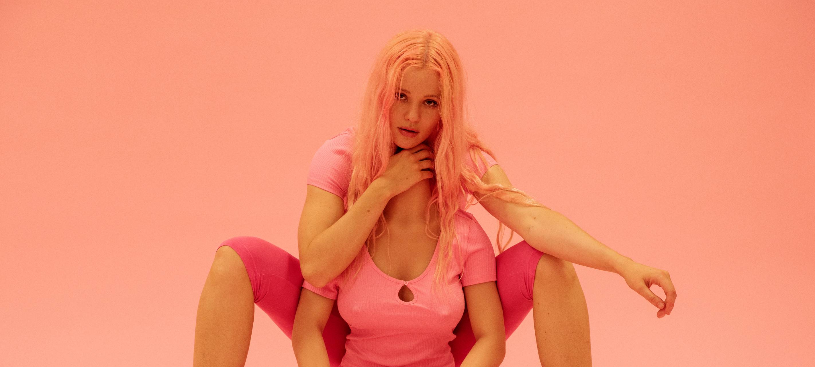 Zwei engumschlungene Frauen mit rosa Klamotten. Sie wirken innig.