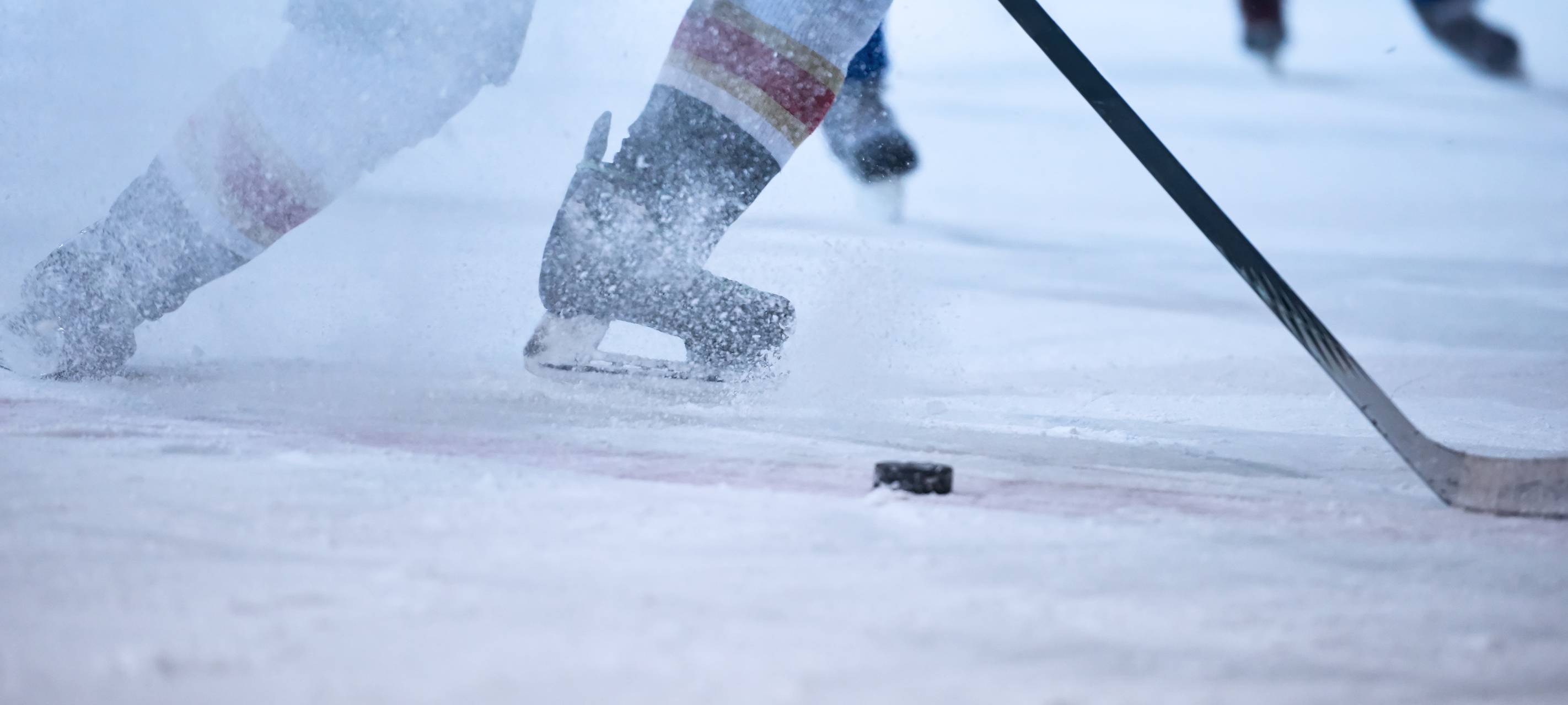 Ein Eishockeyspieler in Aktion. Das Eis spritzt.