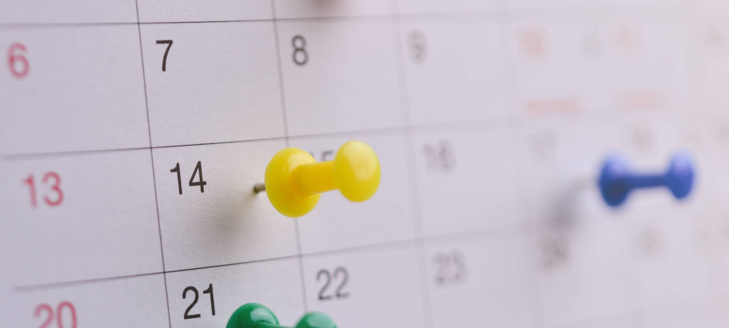 Nahaufnahme eines Steckpins auf einem Kalender, Symbol für Terminvereinbarung, Geschäftsmeeting-Planung oder Reiseplanung.