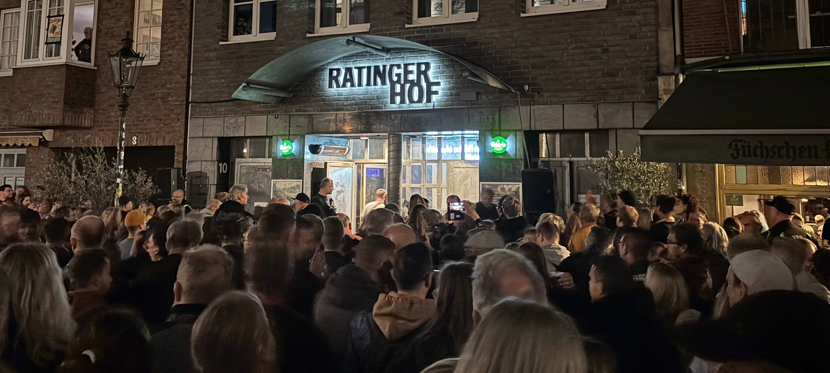 Fans der Toten Hosen verfolgen auf der Ratinger Straße per Lautsprecher ein Konzert der Toten Hosen im Ratinger Hof.