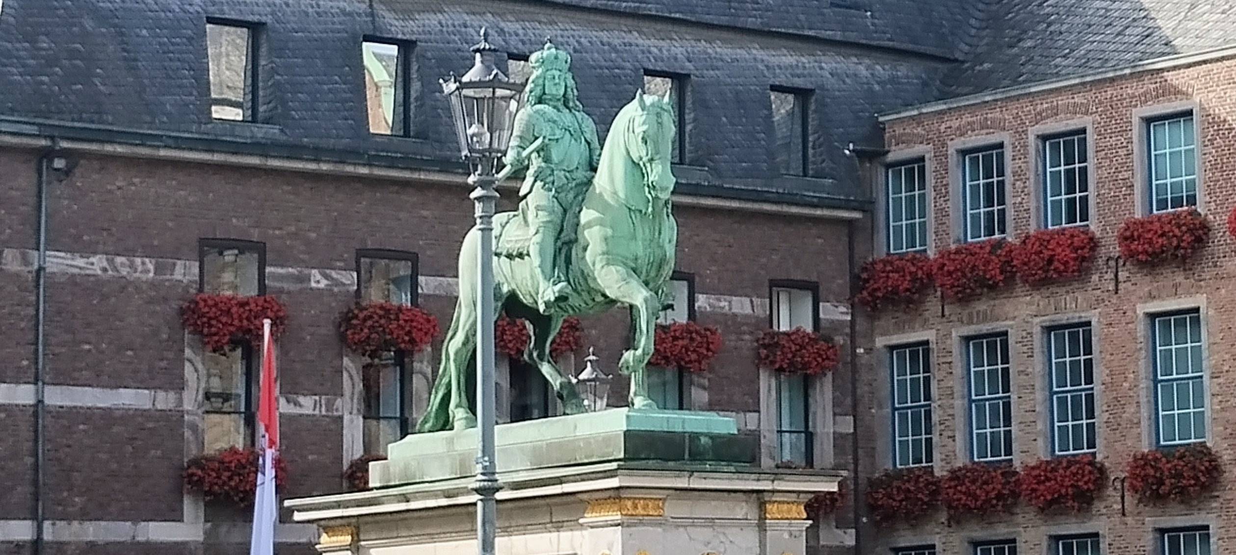 Das Düsseldorfer Rathaus mit bepflanzten Geranienkästen in der Altstadt. Davor steht die Statue von Jan Wellem.